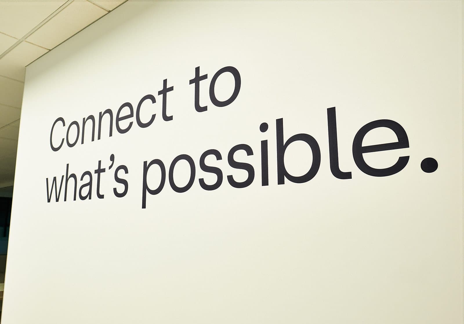 The wall lettering reading "Connect to what's possible." photographed close and at an angle in the Belden St. Louis office, environmental brand detail photography