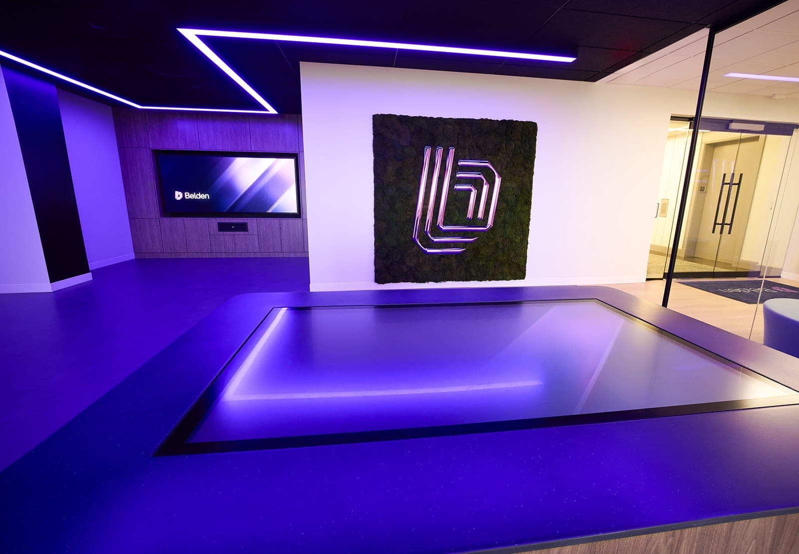 The Belden experience center in St. Louis with the interactive touch table, the LED video wall and the moss wall all in one frame, lit only by the screens, architectural photography by Henry David Photography
