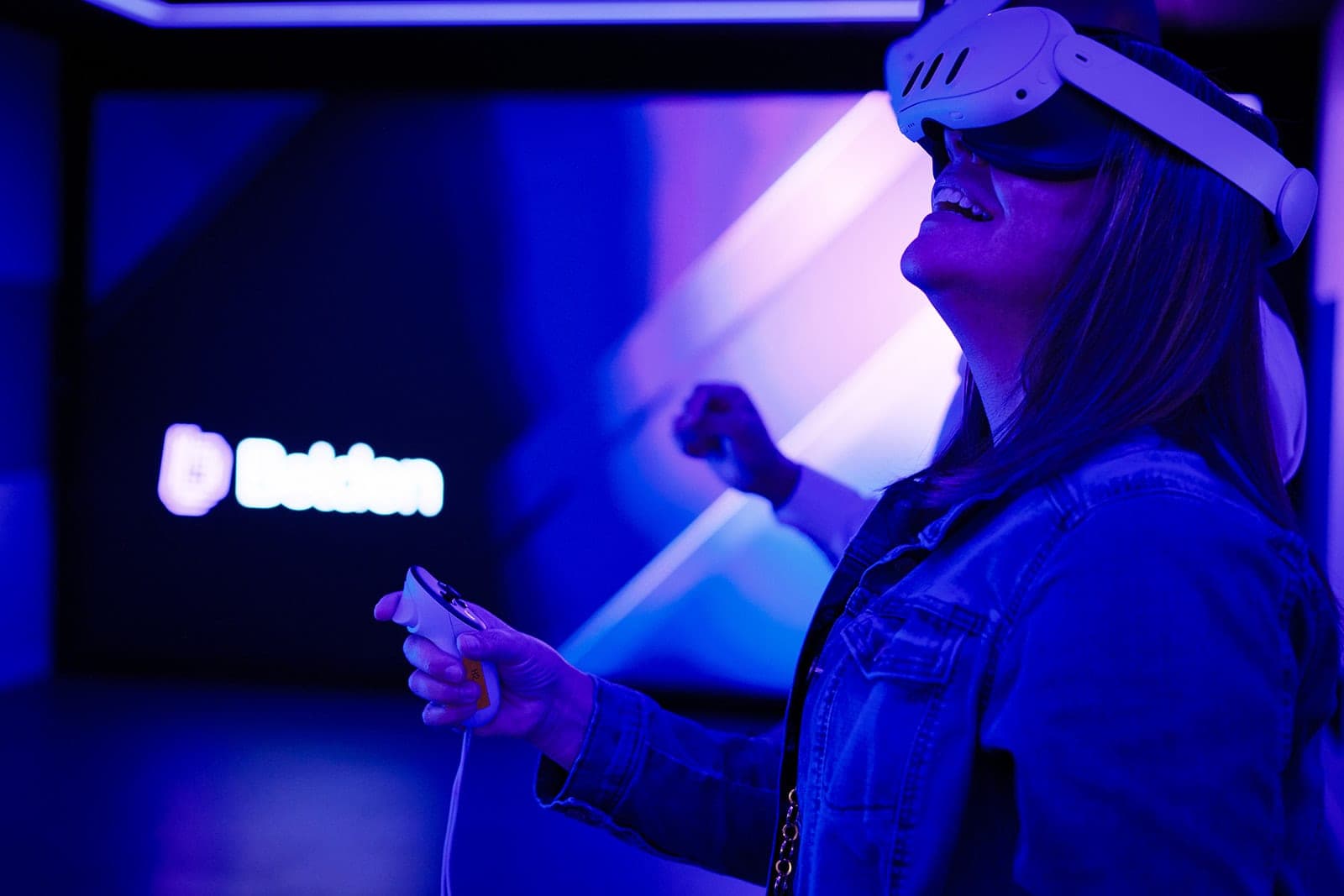 A reaction caught mid-demonstration in Belden's immersive validation lab, controller raised, VR headset on, candid corporate photography in St. Louis