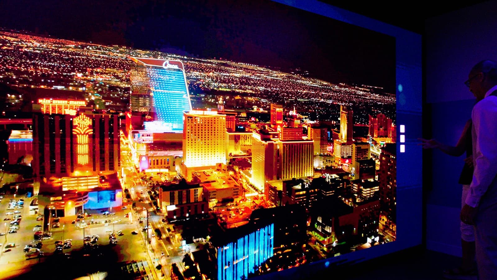A frame from the Belden brand film: the LED video wall filling with an aerial night cityscape while a silhouetted figure stands at its edge, cinematic corporate video in St. Louis