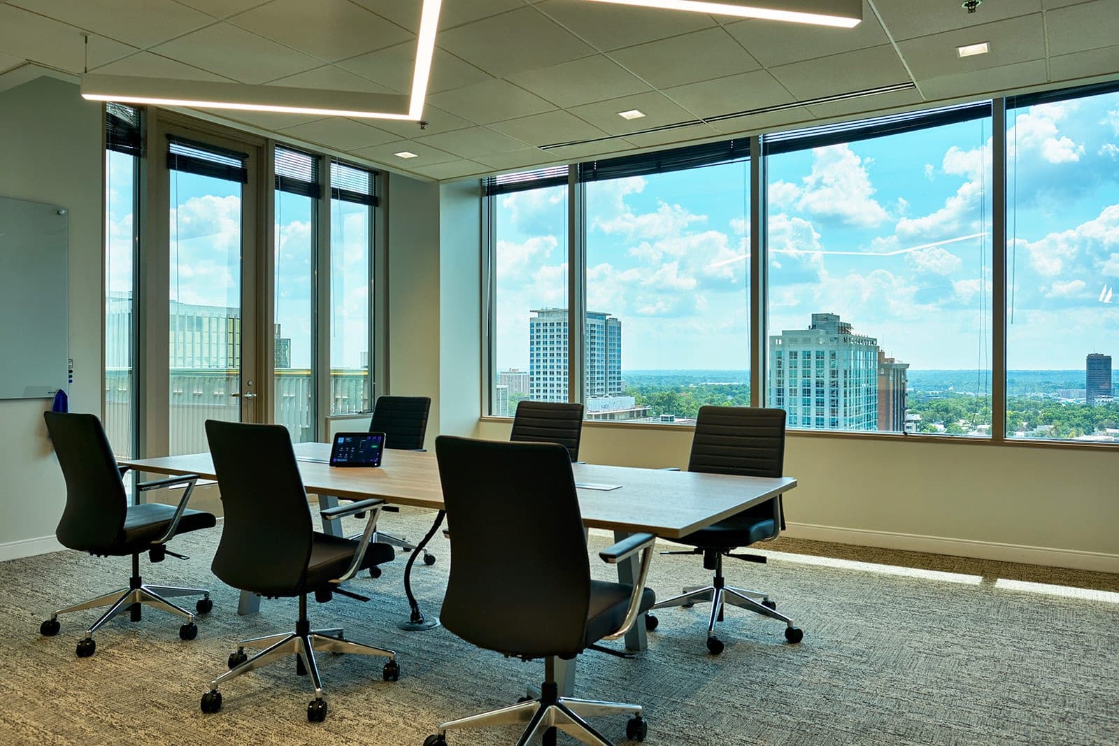 A daylit meeting room at Belden in St. Louis with a wood table, black chairs and a high-rise view through floor to ceiling glass, workplace photography