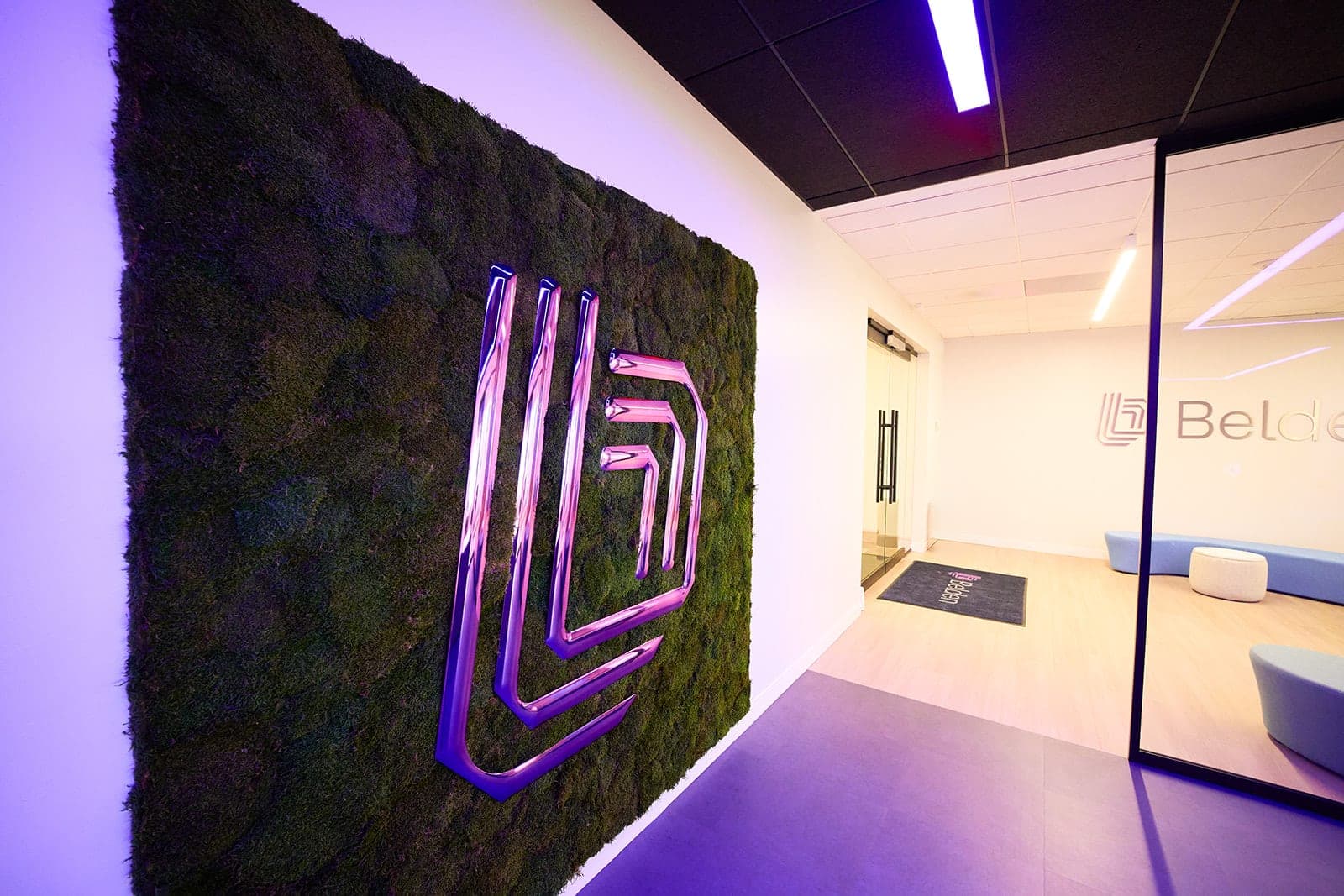 The preserved moss wall running down the corridor of the Belden Customer Innovation Gateway toward the daylit entry beyond, architectural photography for a St. Louis corporate interior