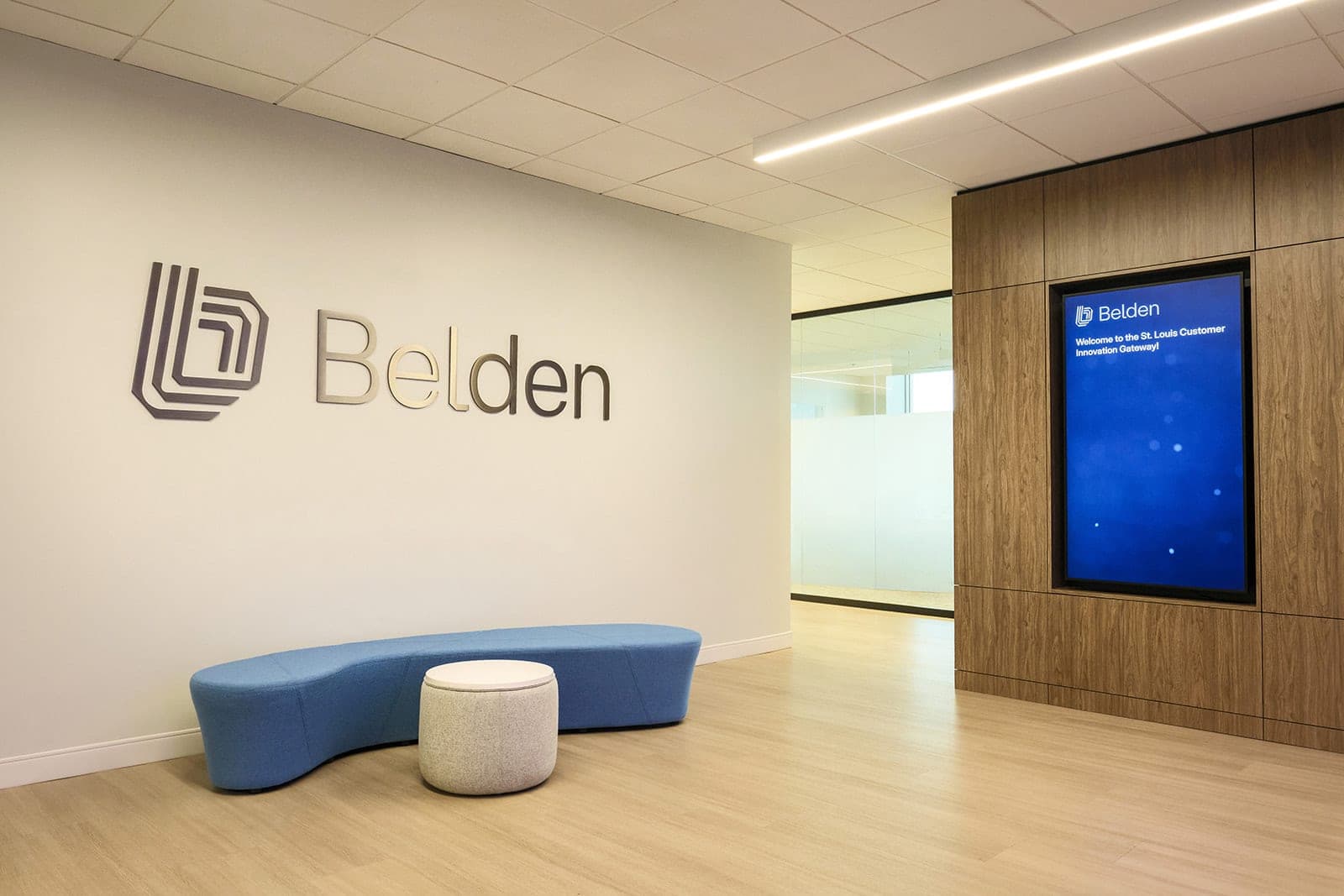 The Belden brand wall and illuminated welcome screen at the St. Louis office entrance, photographed with no one in the room so the architecture and signage carry the frame