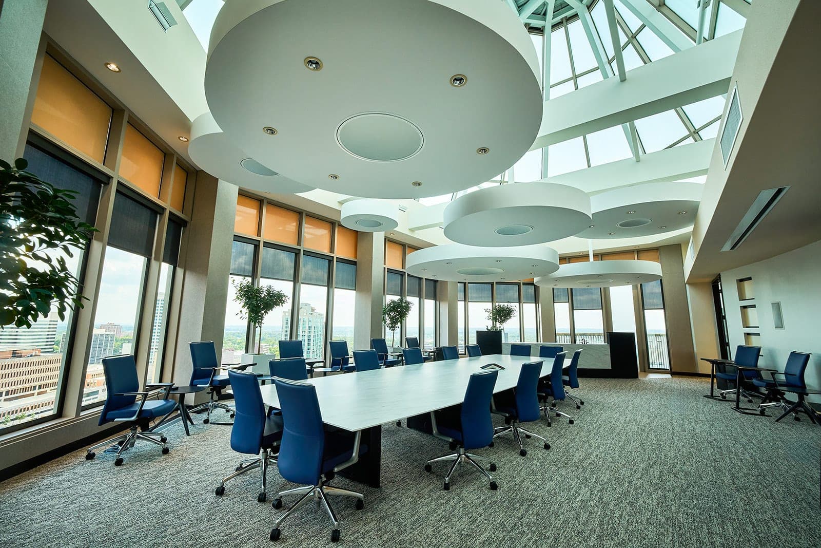 The skylit boardroom at Belden's St. Louis office under a domed glass ceiling, with a long white table, blue leather chairs and the city beyond the windows, architectural photography by Henry David Photography