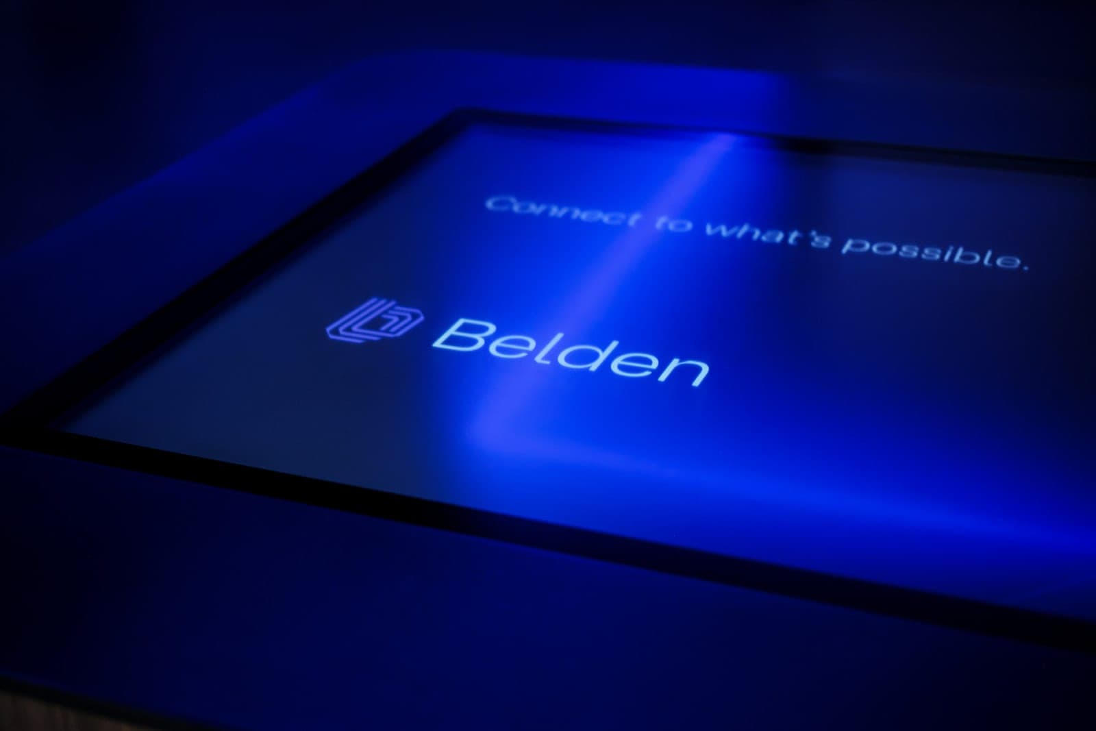 The glass surface of the Belden touch table raking away from the camera as a field of blue light, abstract detail photography in a St. Louis office