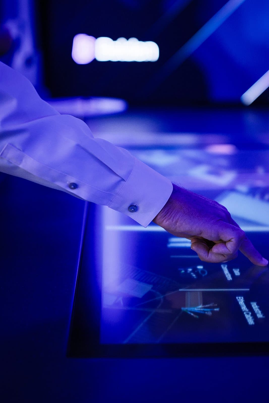 Close frame of the Belden touch table screen showing product categories including data connectors and industrial ethernet cables, screen detail photography for a St. Louis corporate experience center