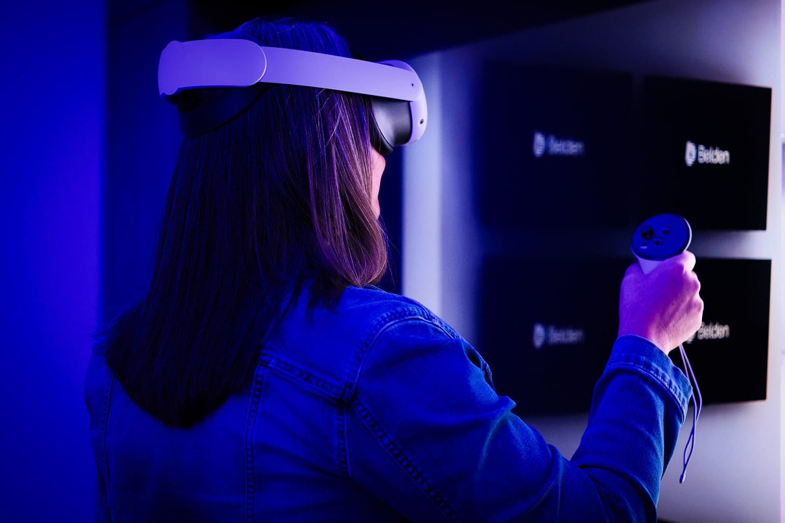 A Belden colleague smiling inside a VR headset in the immersive validation lab, holding a controller, corporate lifestyle photography in St. Louis