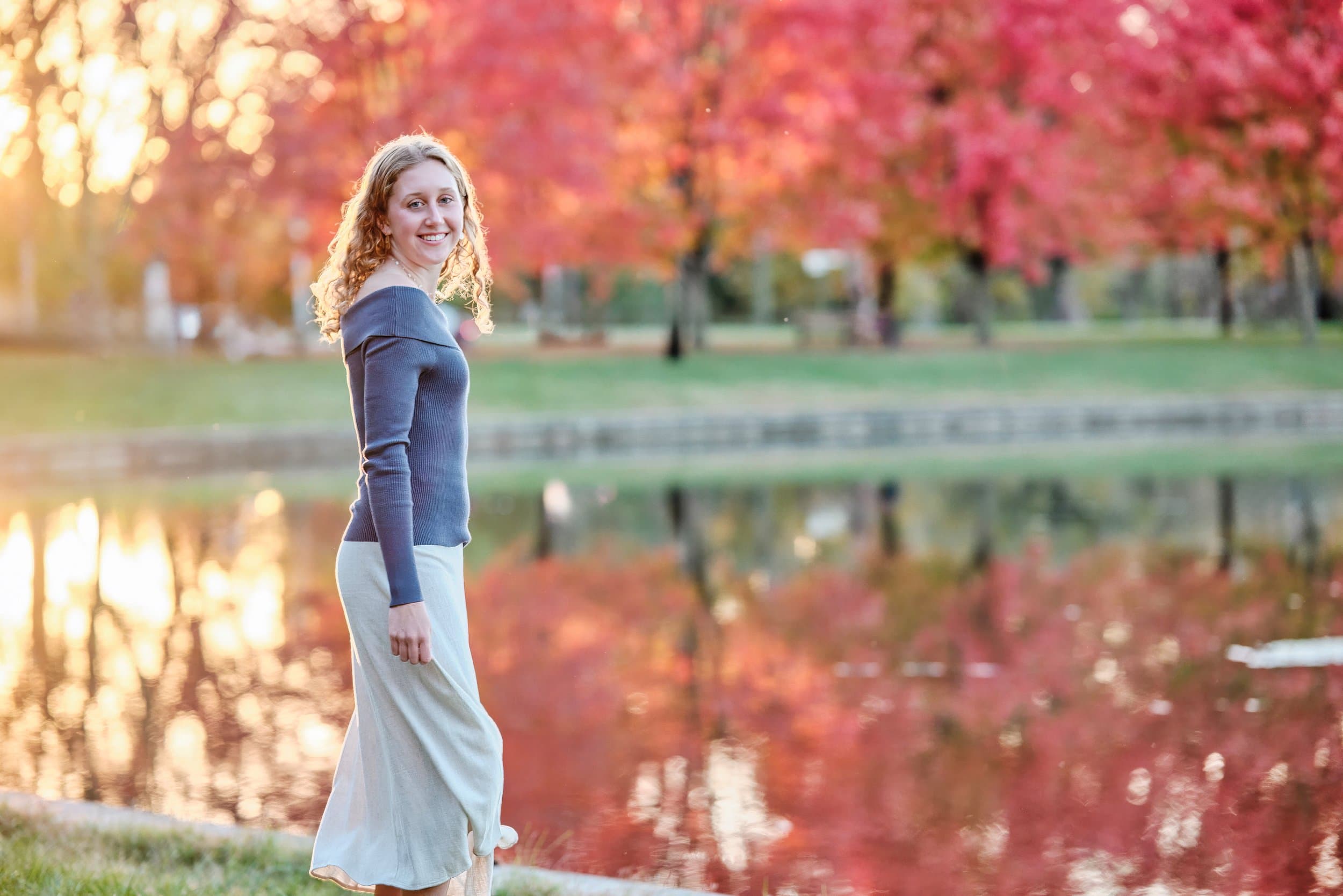 Outdoor portrait subject backlit by setting sun in a St. Louis park, warm rim light wrapping around hair and shoulders during golden hour