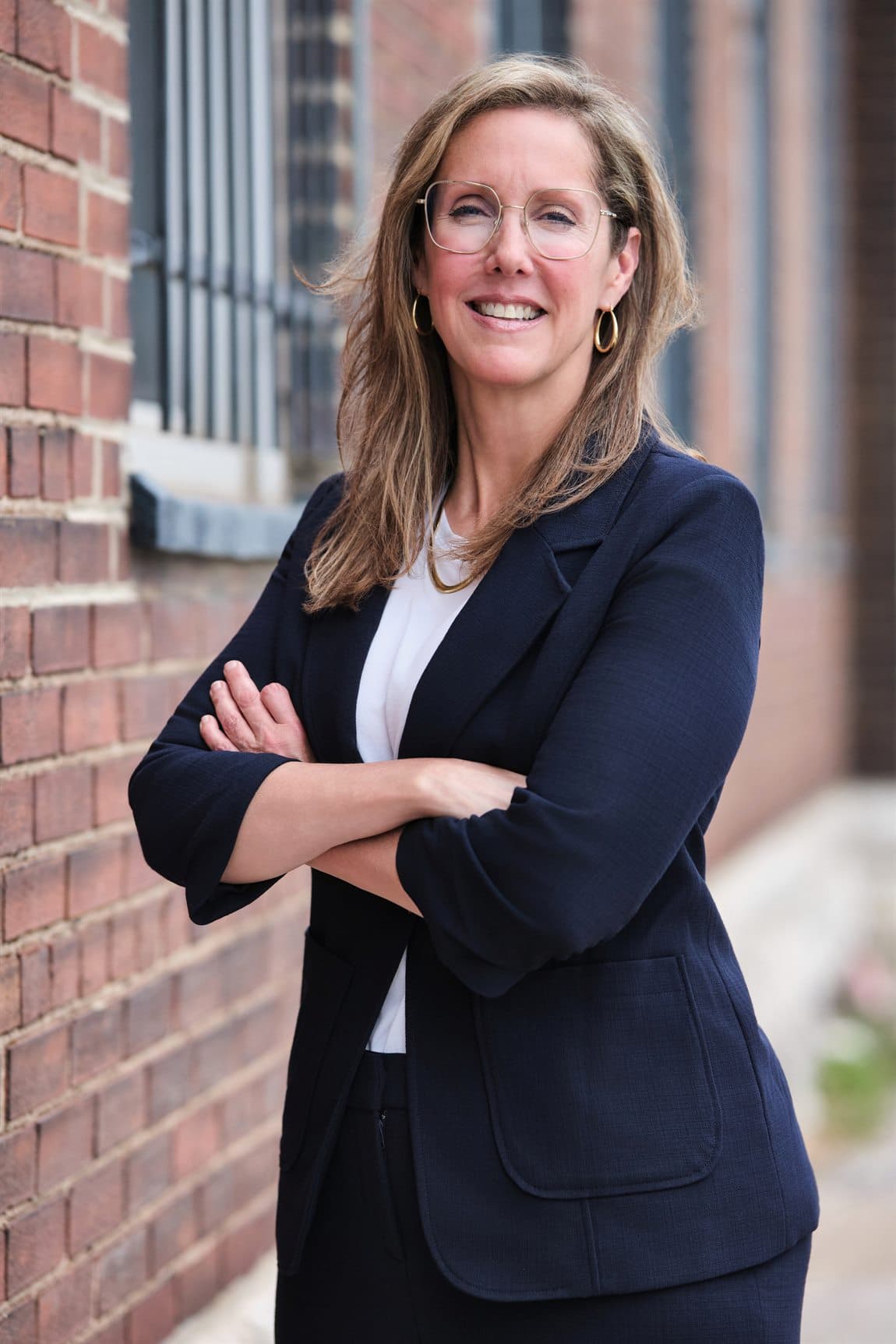 Approachable environmental portrait of a public-facing candidate by a brick exterior