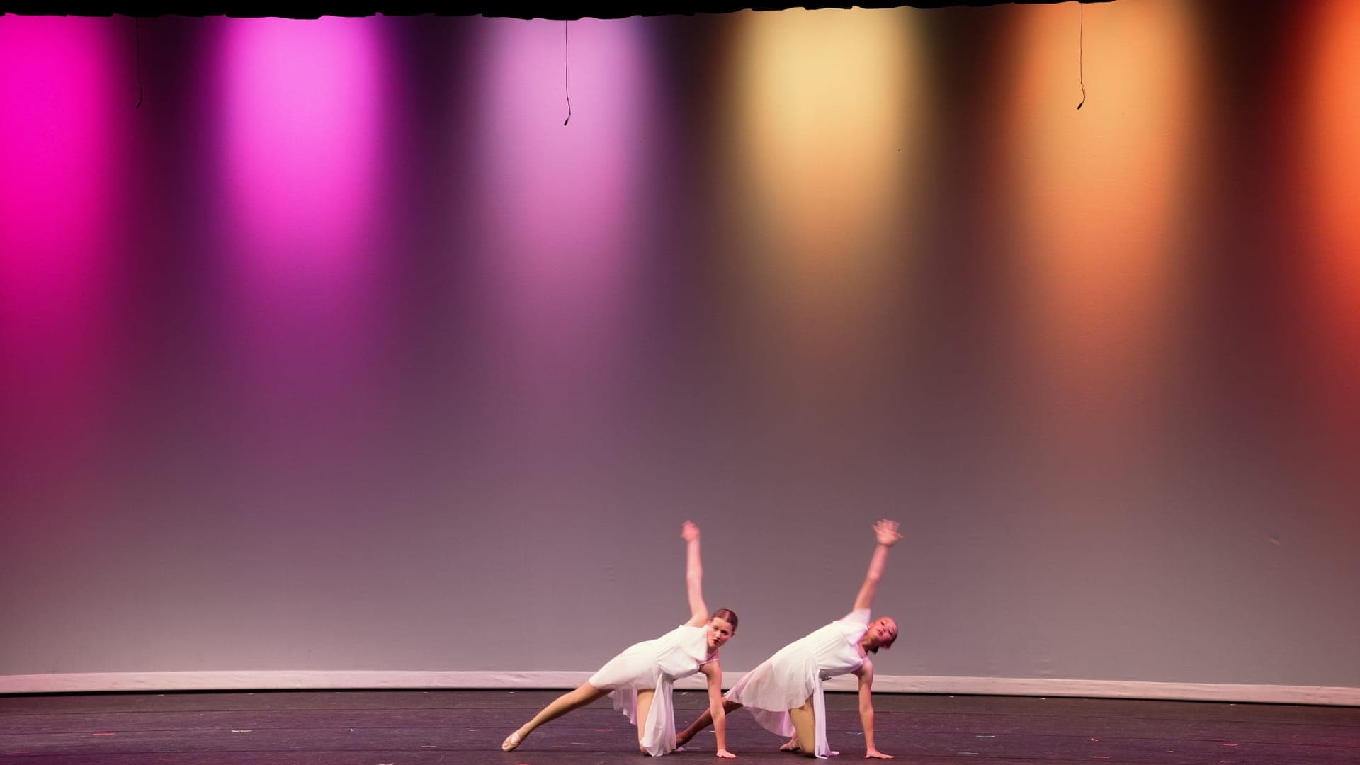 Two lyrical dancers in white hold a low mirrored pose on a St. Louis dance recital stage