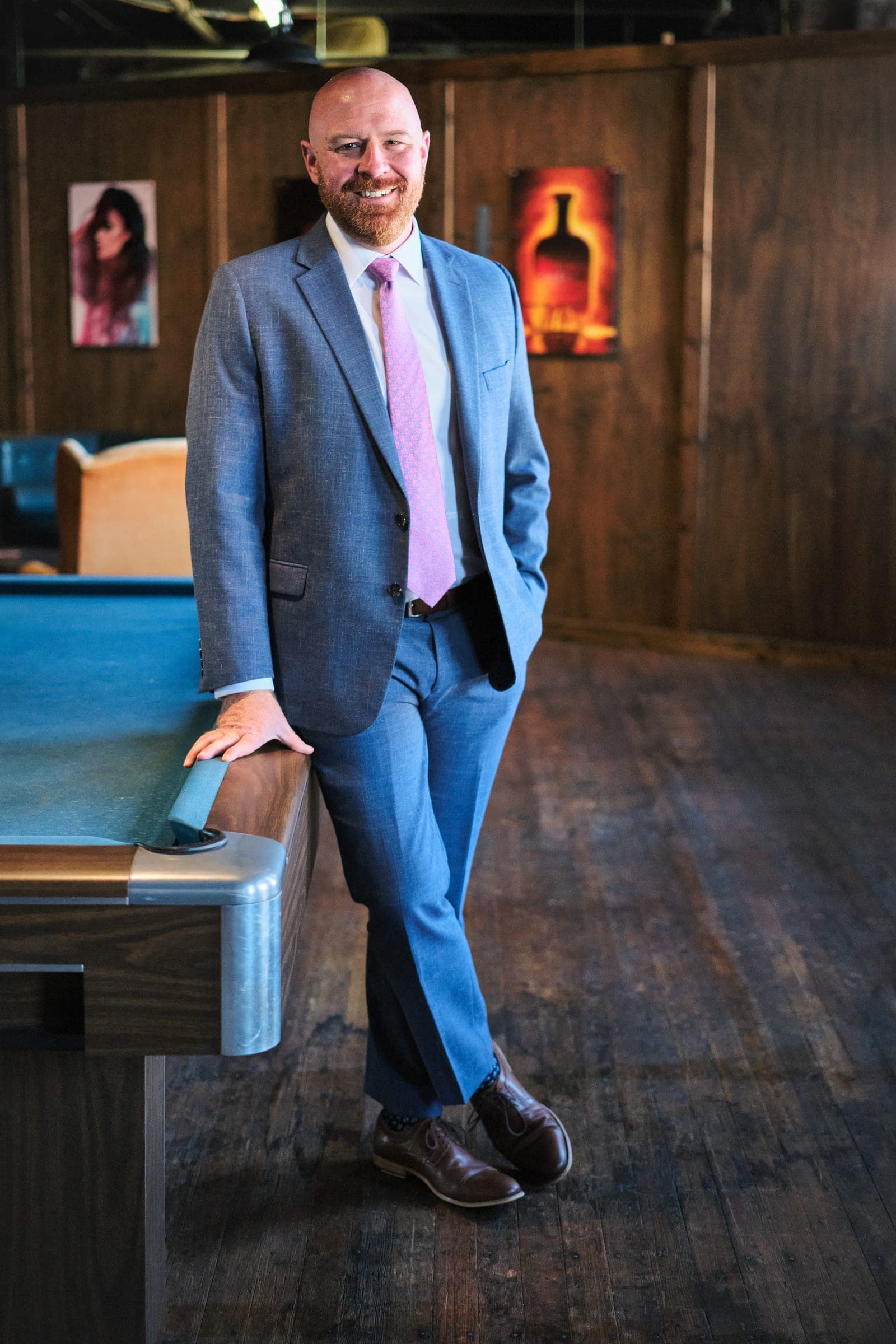 Attorney at The Dixon Injury Firm in a light blue suit leaning on a pool table in a wood-panelled room, environmental portrait in St. Louis by Henry David Photography