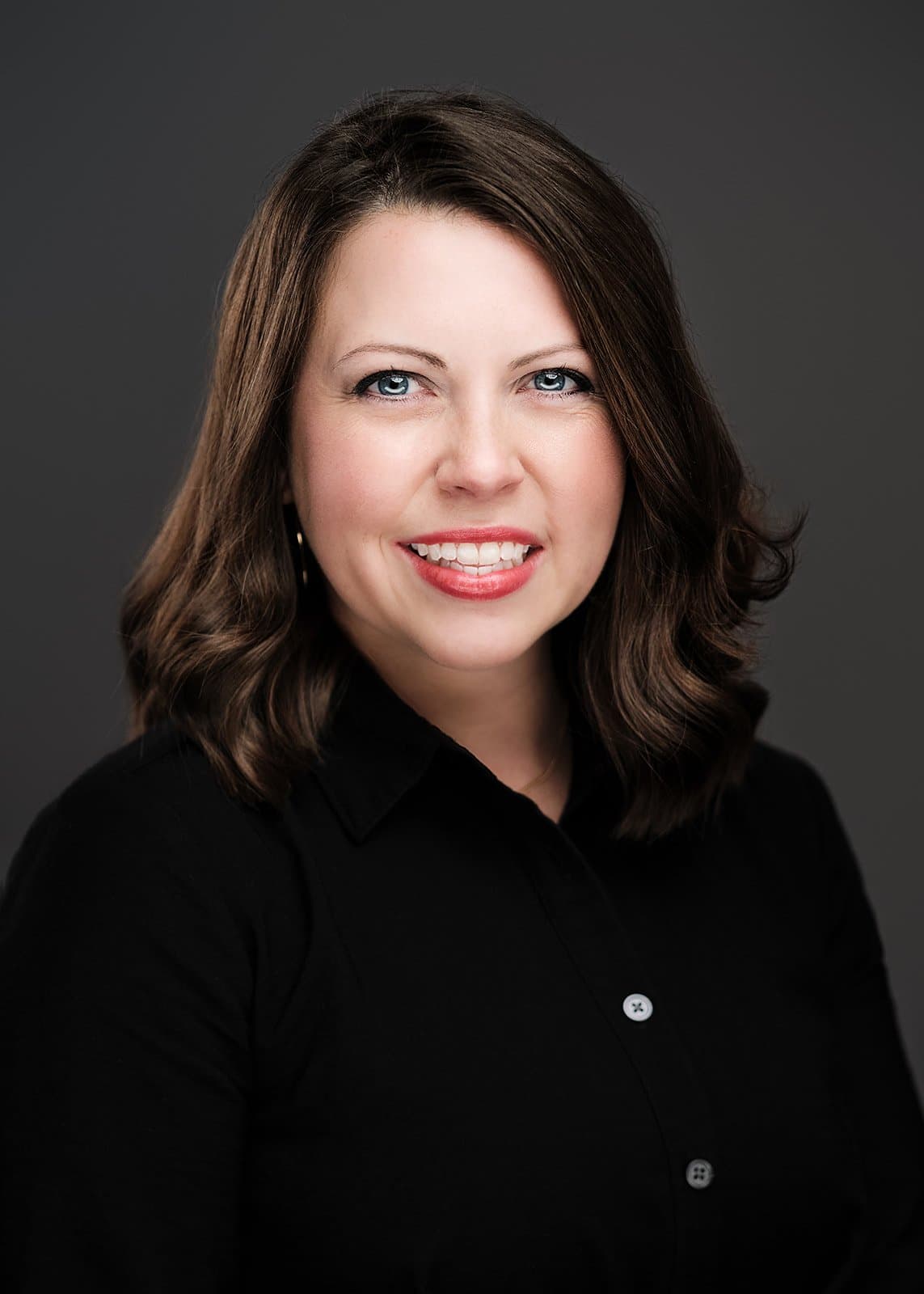 Woman with a dark bob in a black top, photographed at a conference headshot booth