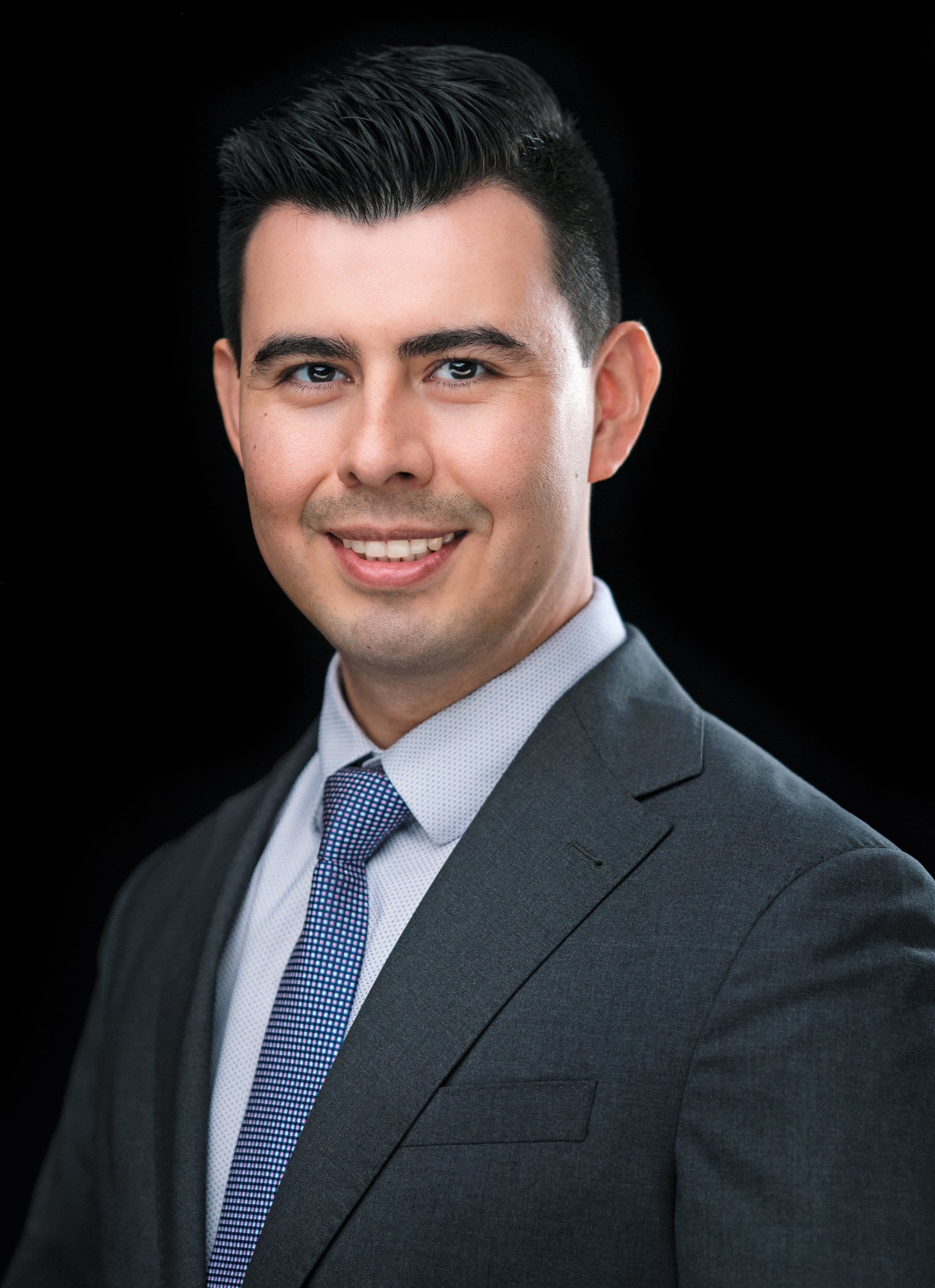 Smiling man in a grey suit and blue tie, photographed at our headshot booth at a business expo