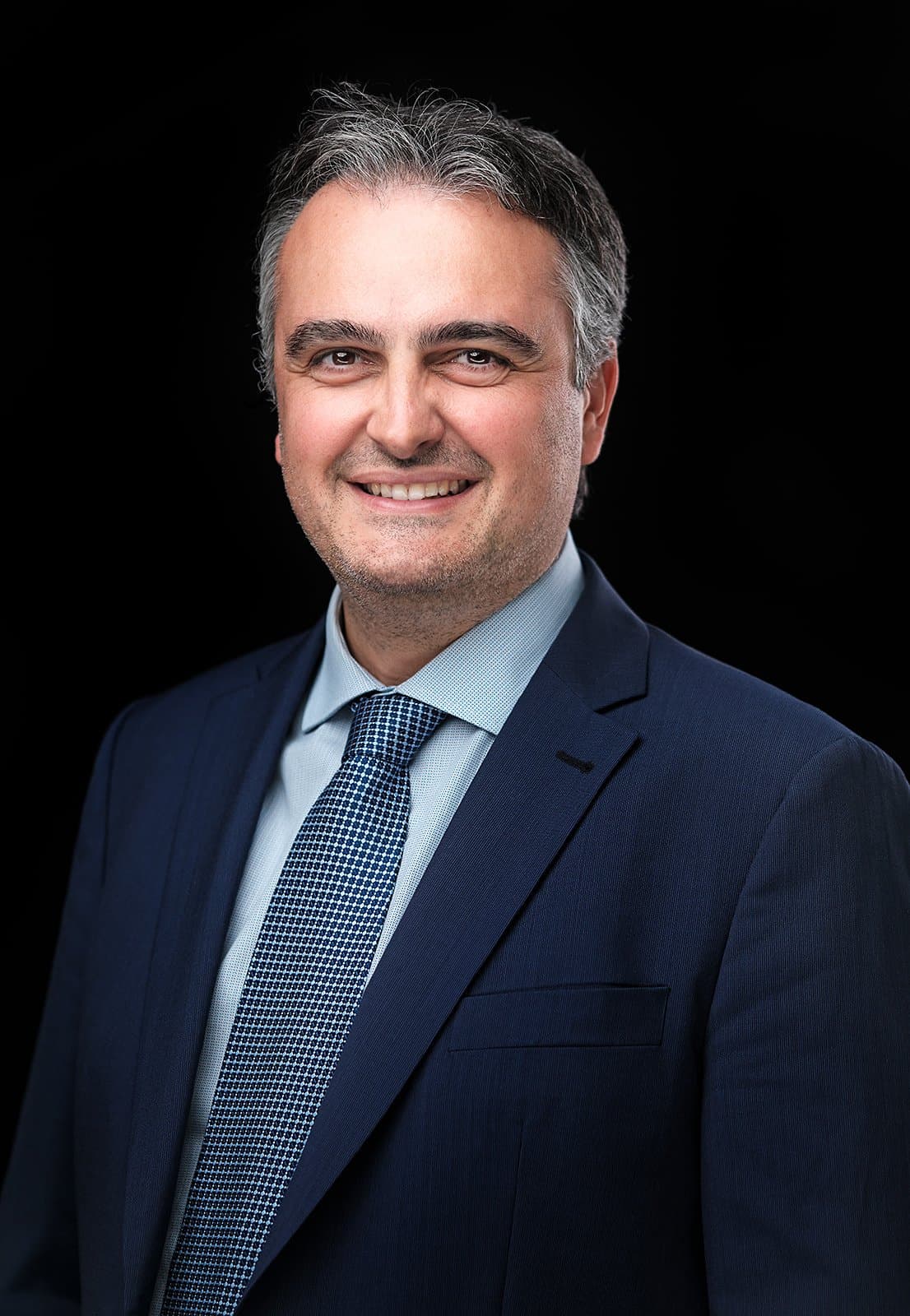 Conference attendee in a navy suit and blue tie, photographed at our on-site headshot booth