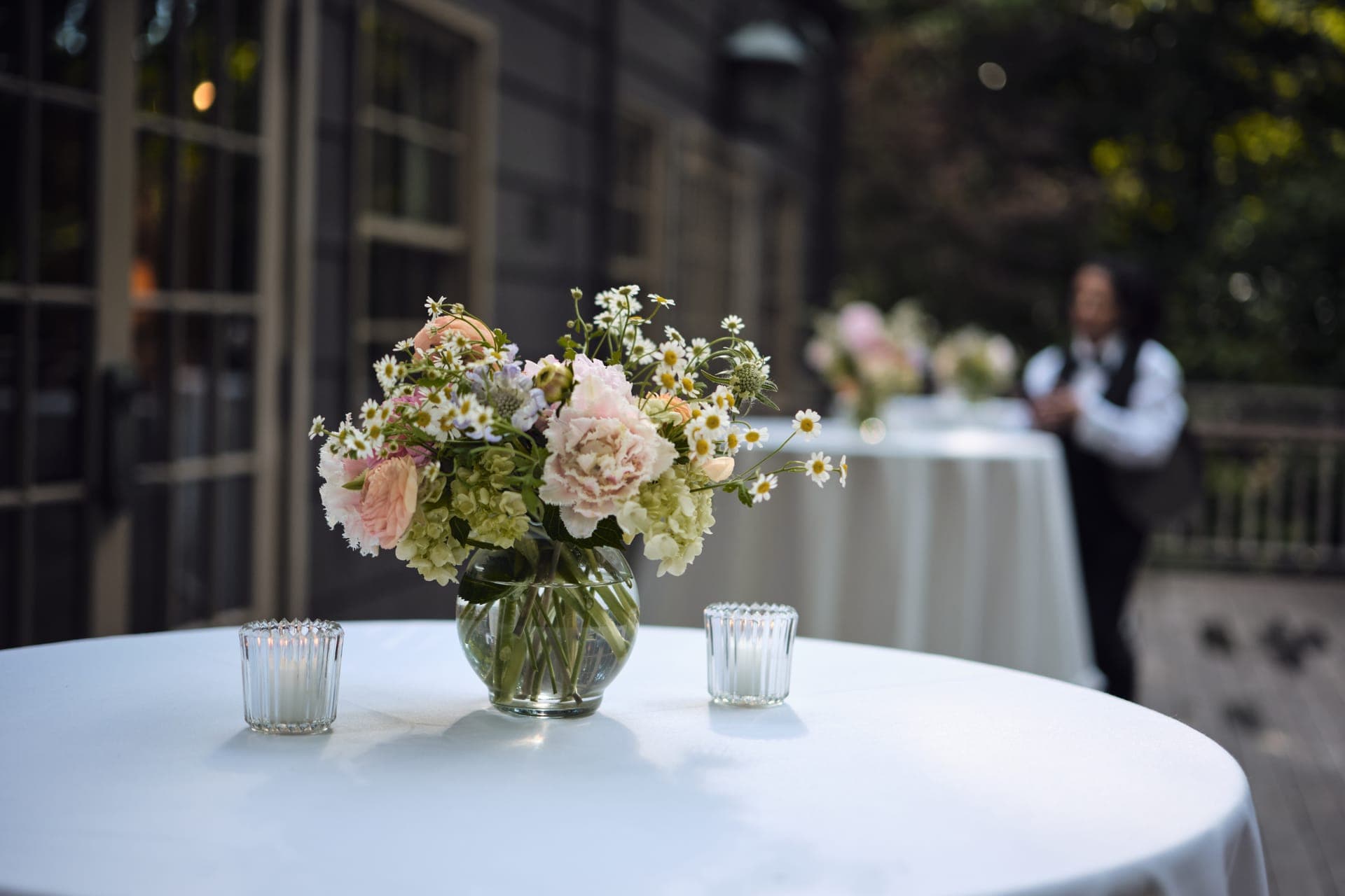 Cocktail tables with flowers and candles at dusk on the Deer Creek Club terrace in Ladue