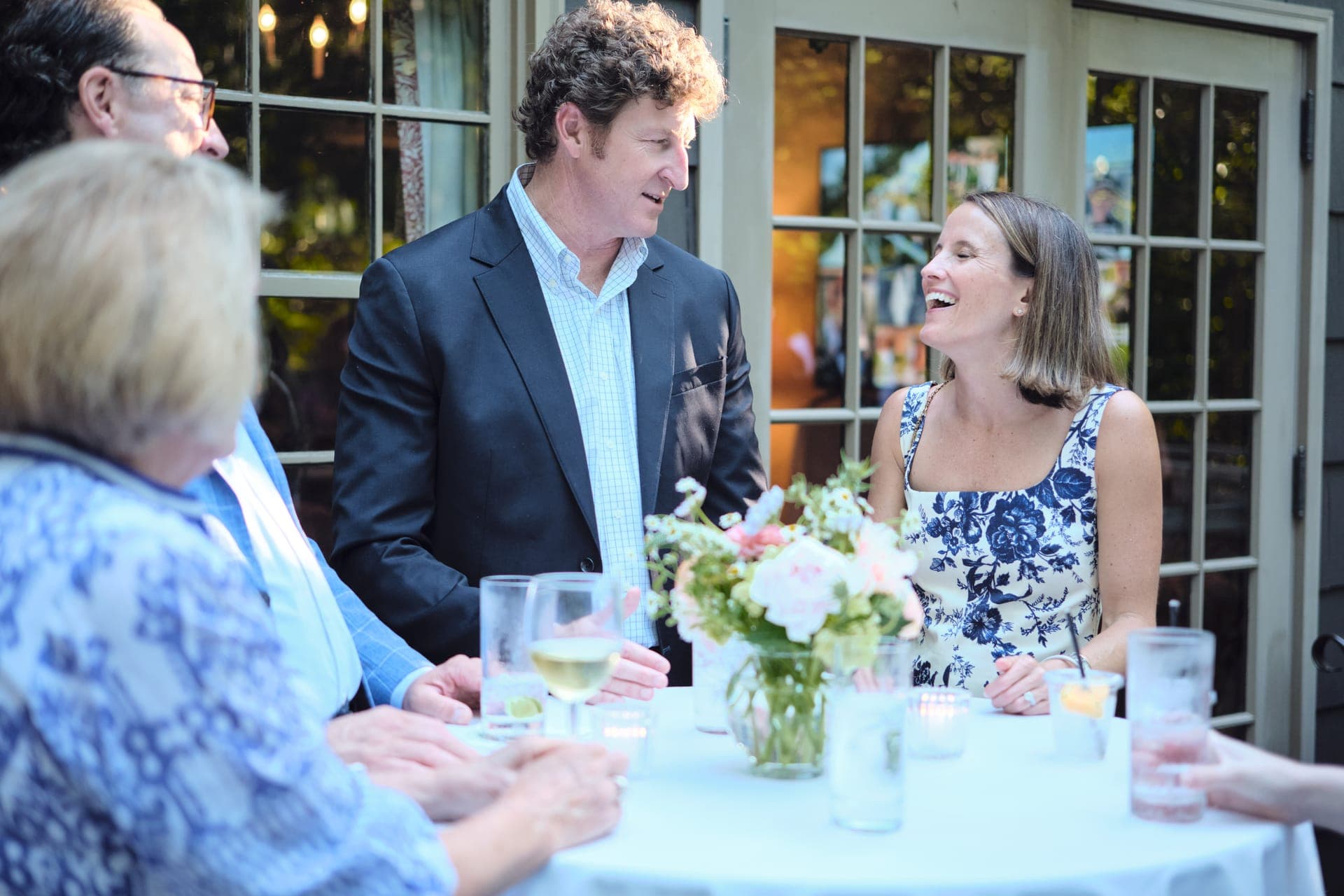 A couple laughs across a flower topped table at a family reunion dinner in Ladue