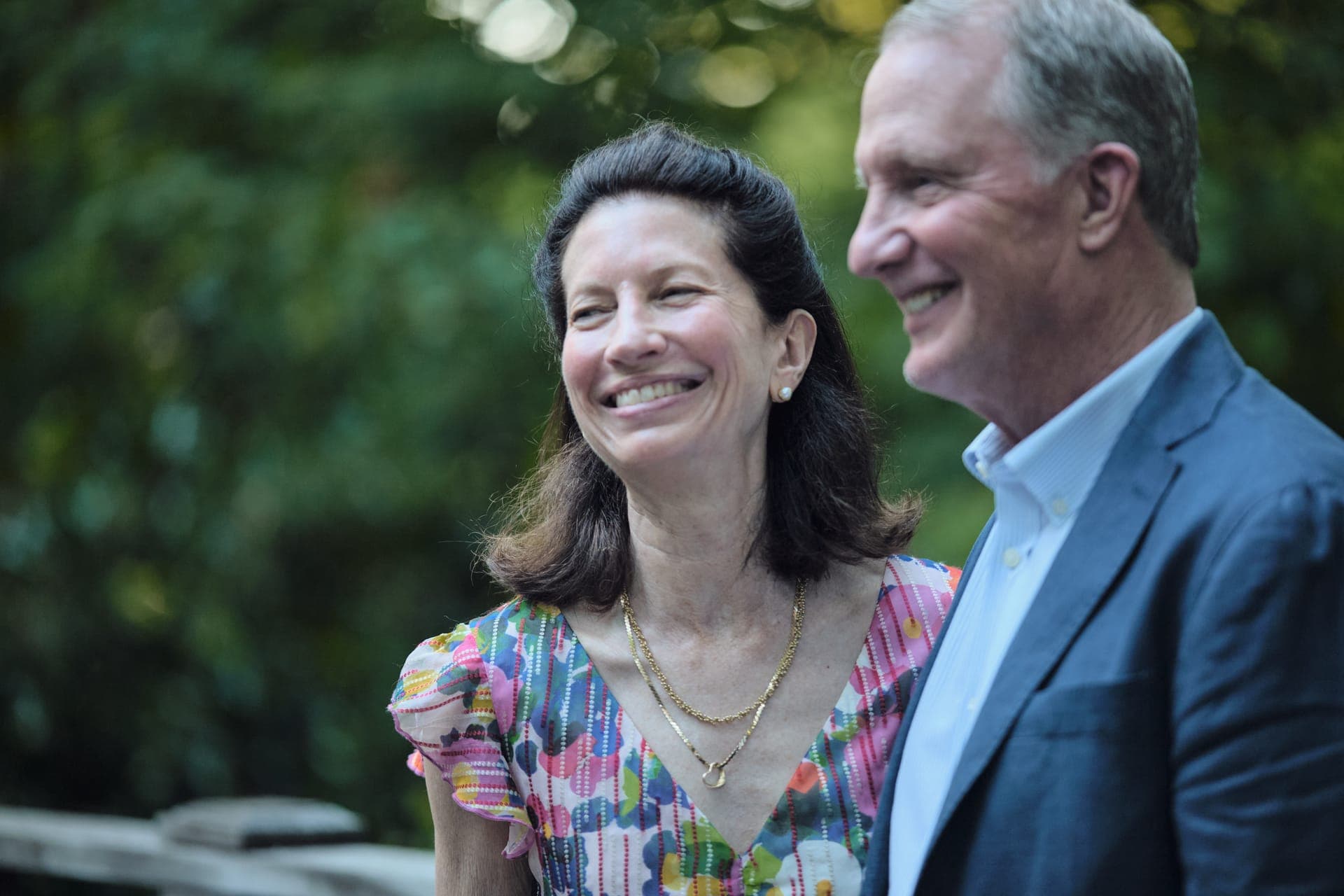 A couple laughs together in golden hour light on the bridge at Deer Creek Club in Ladue