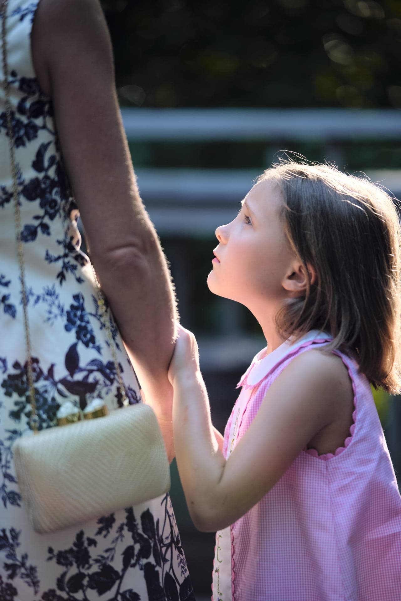 A young girl looks up at her mother and holds her hand at a family reunion in Ladue