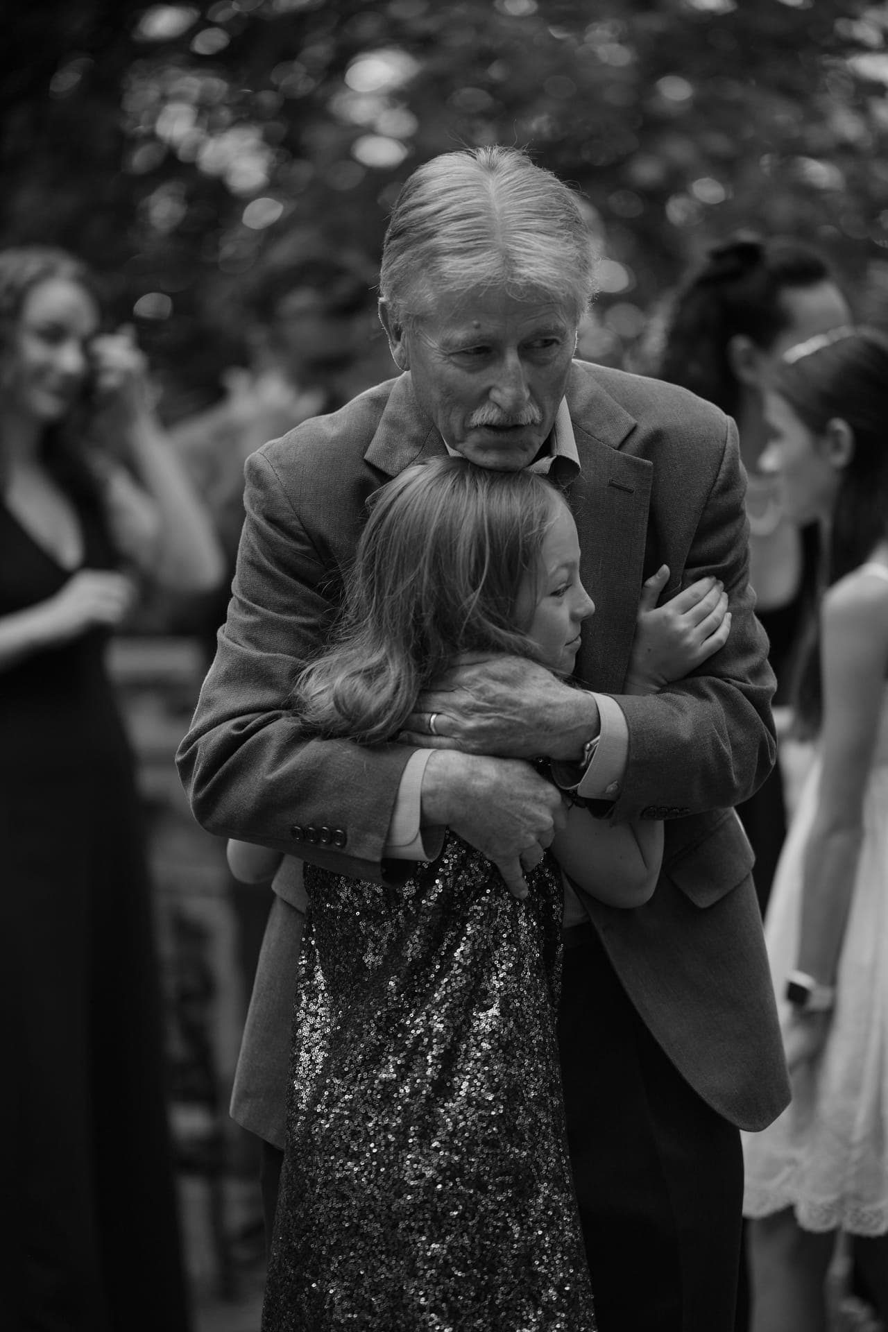 Black and white photo of a grandfather hugging his granddaughter at a family reunion in Ladue