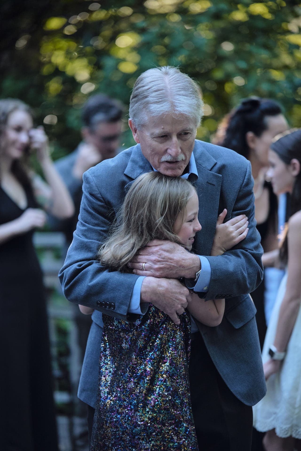 A grandfather wraps his granddaughter in a hug at a golden hour family reunion in Ladue