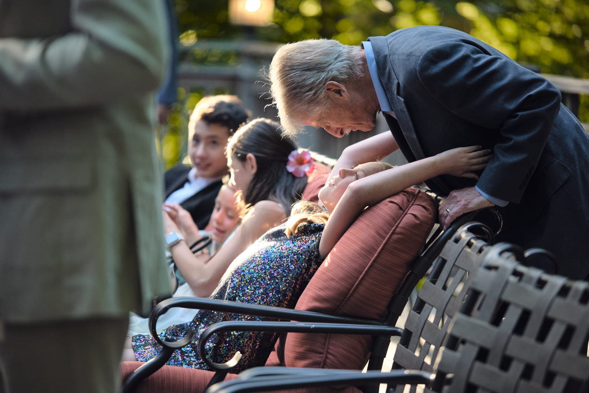 A grandfather leans in to greet the children at a family reunion at Deer Creek Club