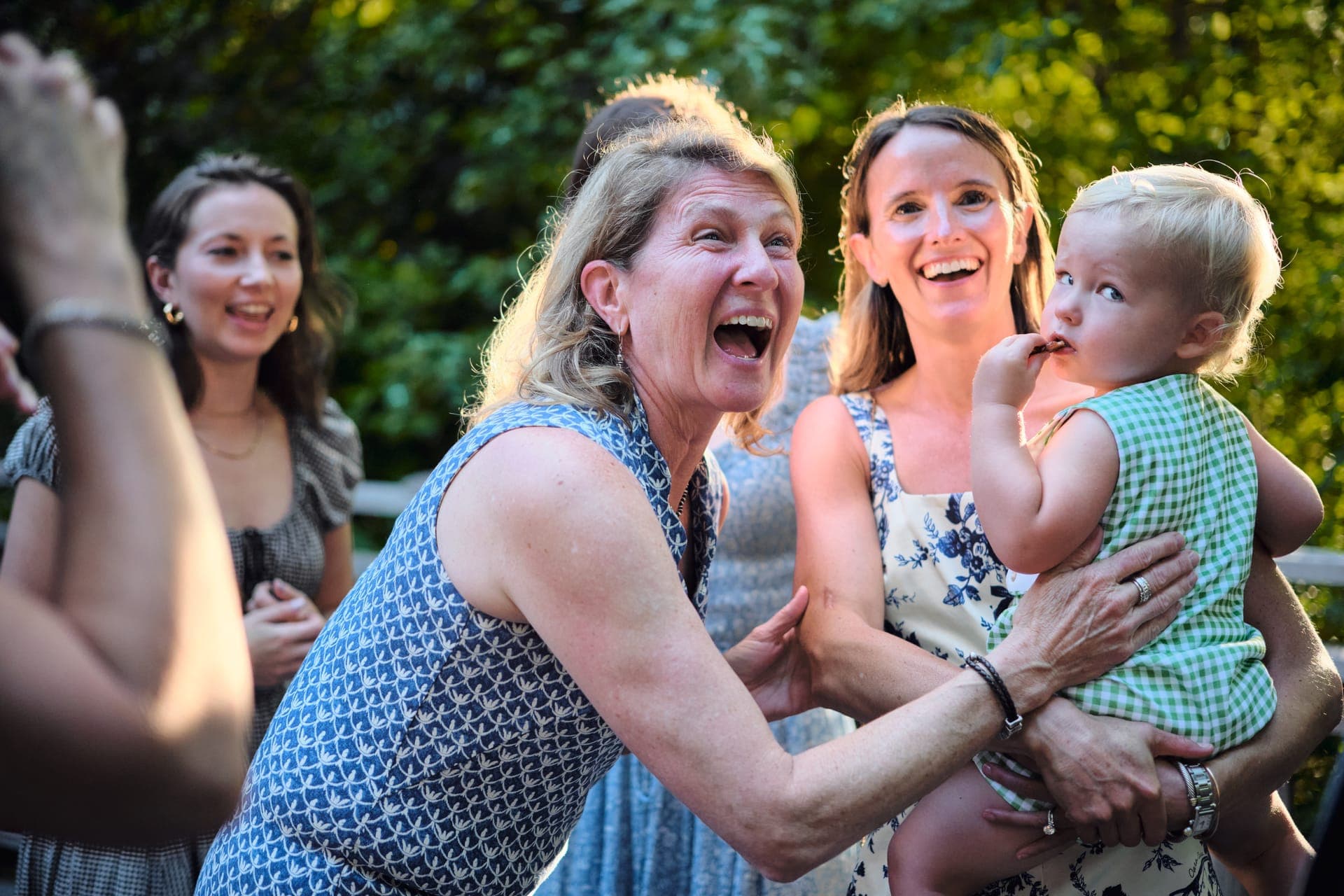 A grandmother laughs with two women at a golden hour family reunion at Deer Creek Club