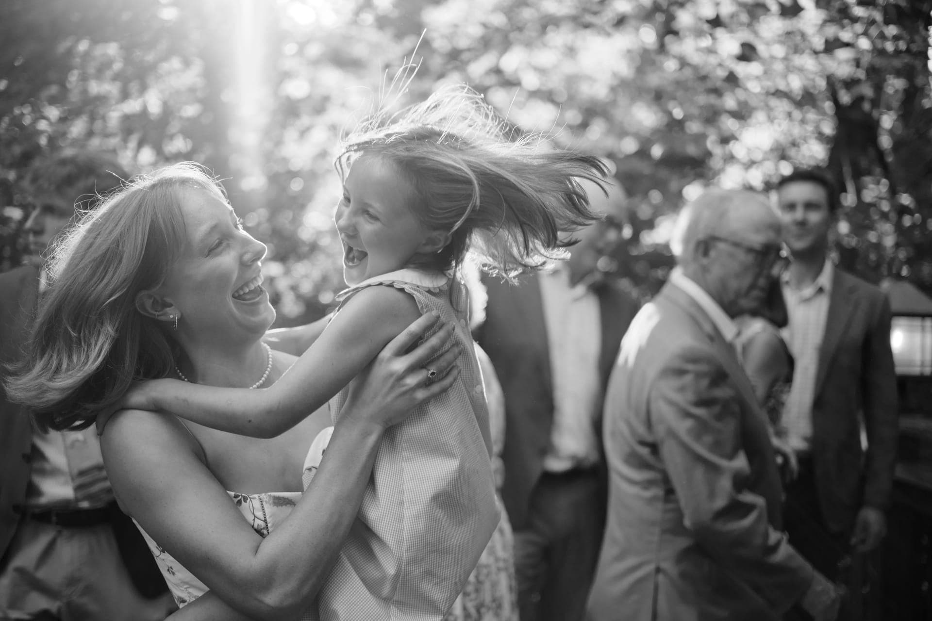 Black and white photo of a mother and daughter spinning into a hug at a family reunion in Ladue