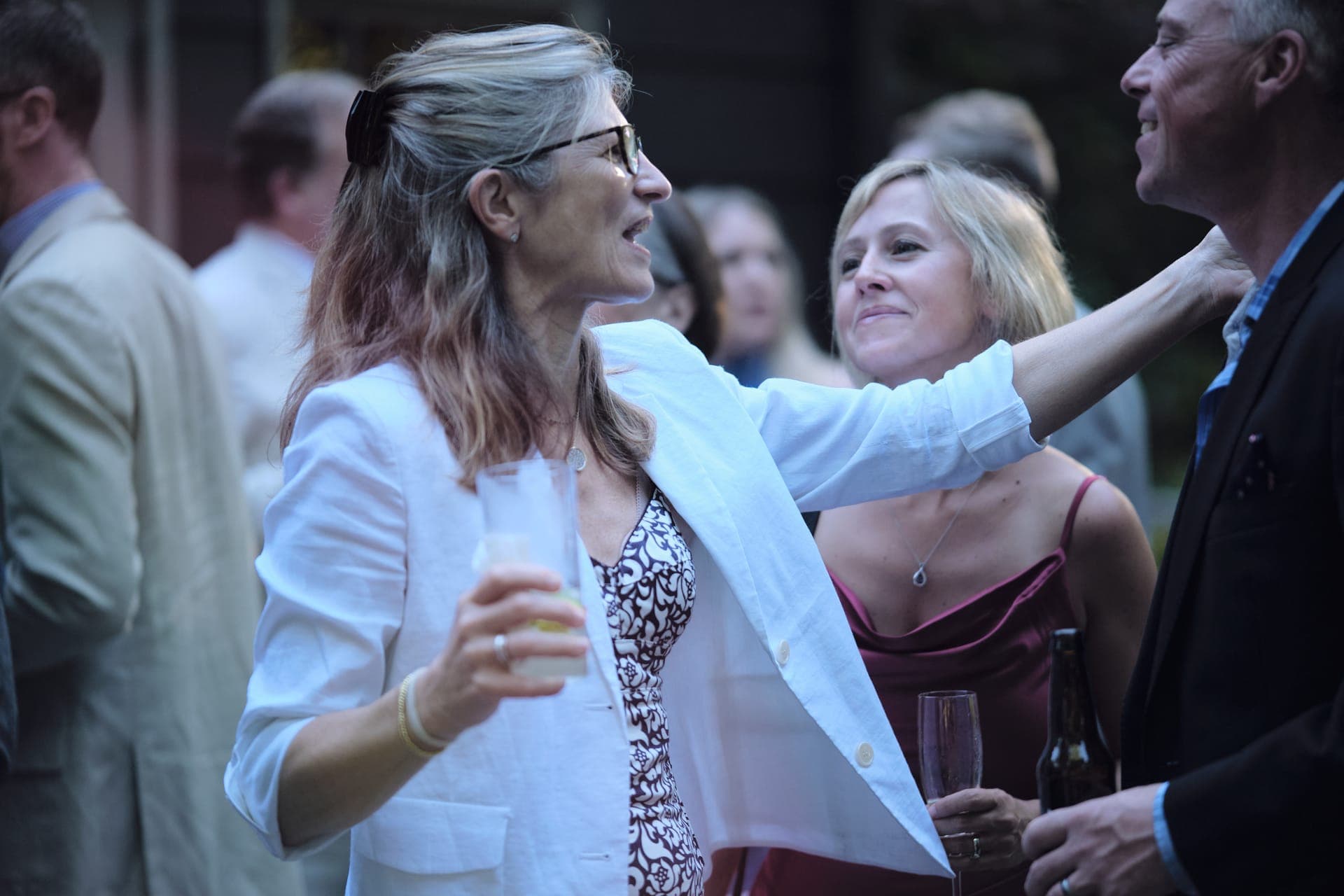 A woman reaches to embrace a relative as a friend looks on at a family reunion in Ladue