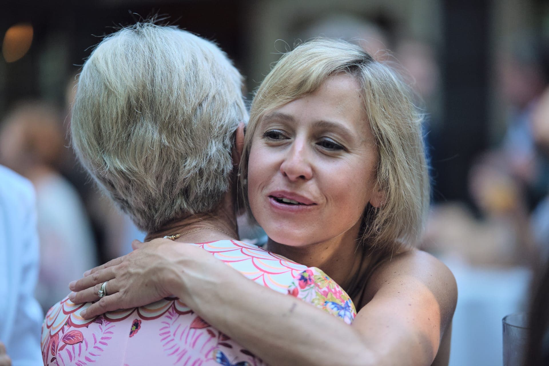 A young woman holds an older woman in a quiet embrace at a family gathering in Ladue