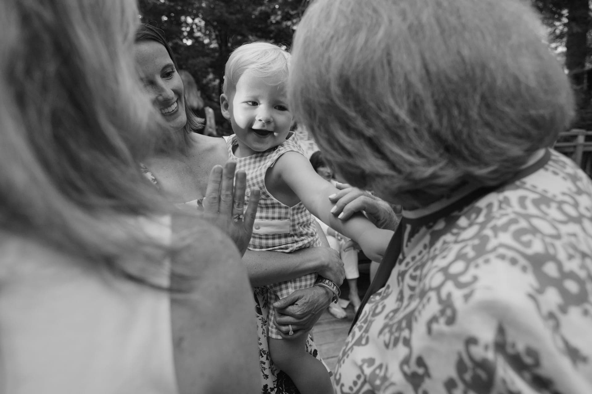 Black and white photo of a baby beaming at a grandmother across three generations at a family reunion