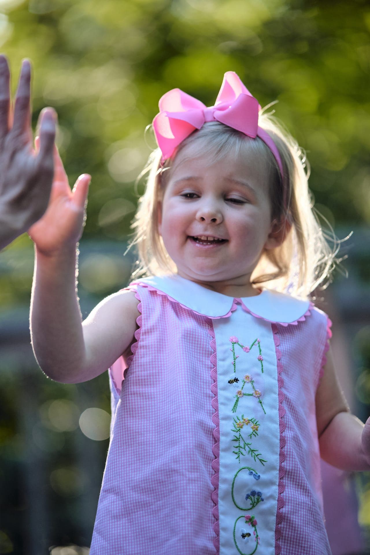 A toddler in a pink bow shares a high five at a family reunion in Ladue