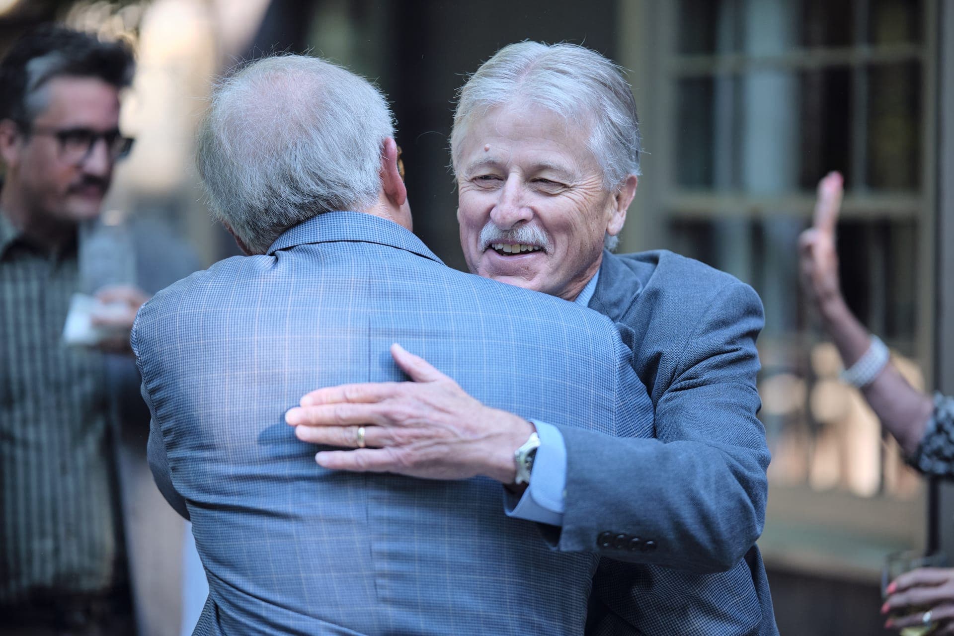 Two men greet each other with a grinning hug at a family reunion in Ladue