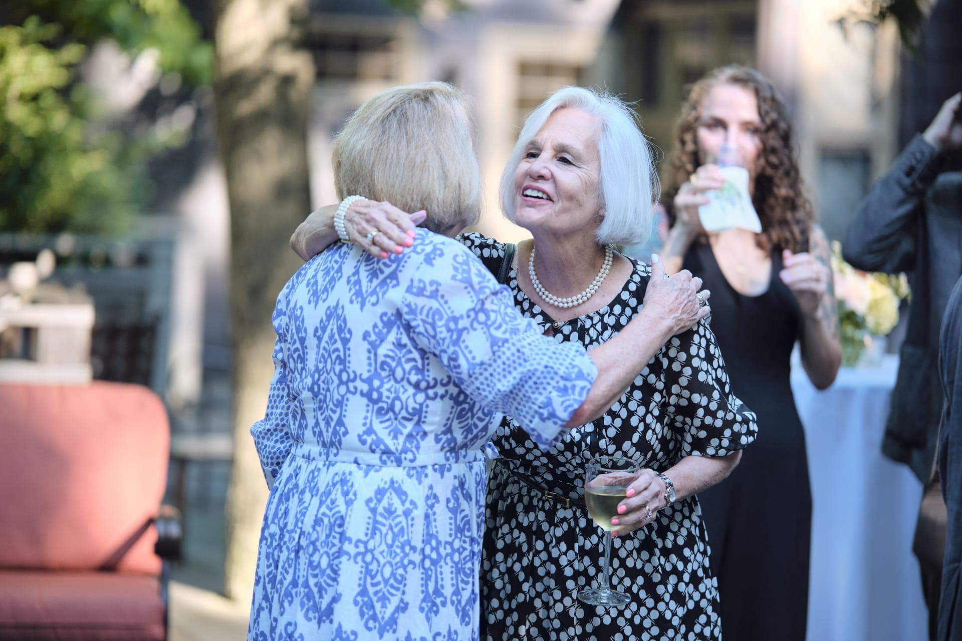 Two women embrace and laugh at a golden hour family reunion at Deer Creek Club in Ladue, photographed by Henry David Photography