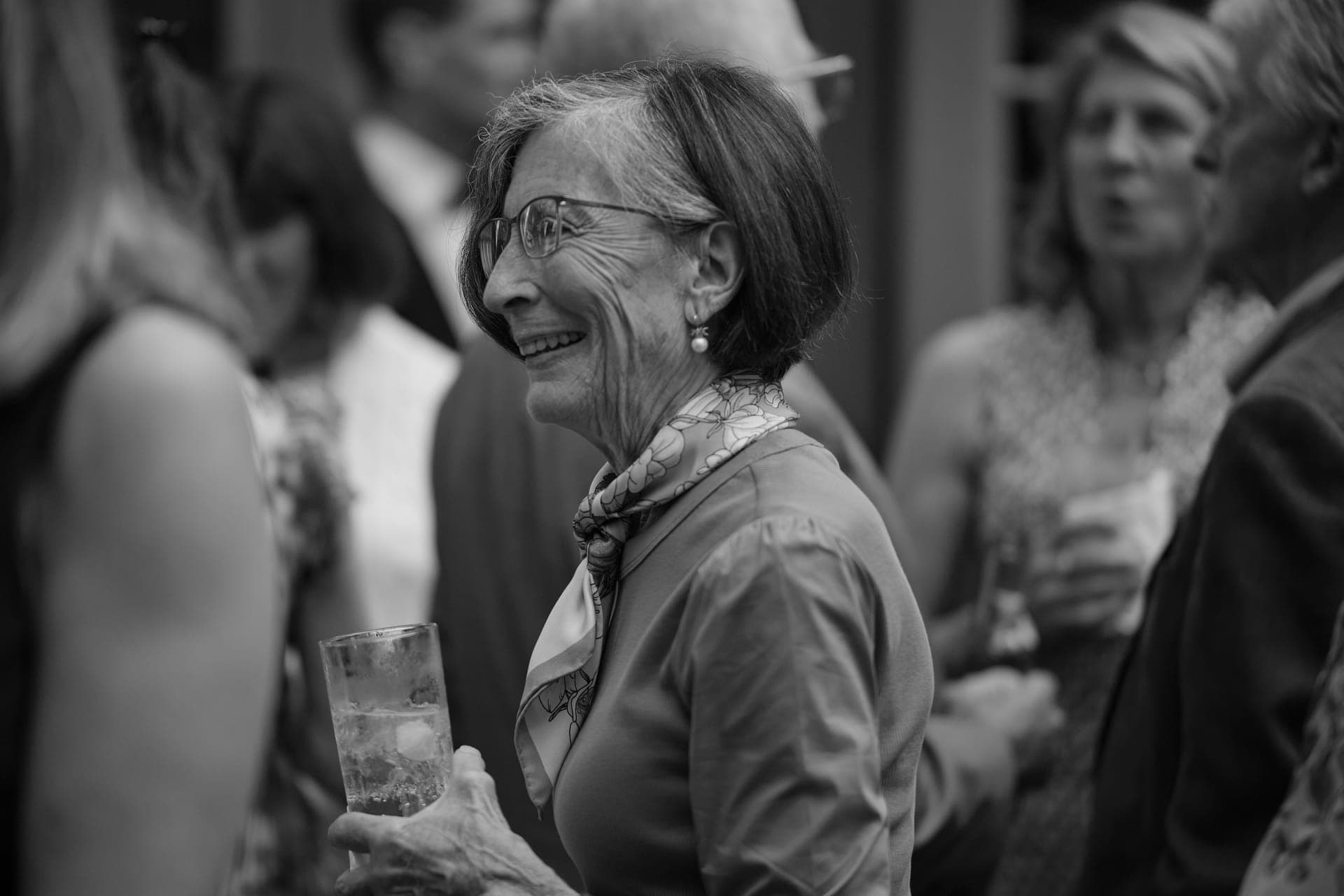 Black and white photo of a woman laughing during cocktail hour at a family reunion at Deer Creek Club in Ladue