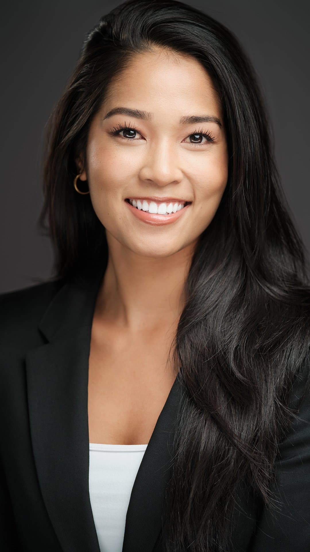 Woman with long dark hair in a black blazer, photographed at our headshot booth at a real estate trade show