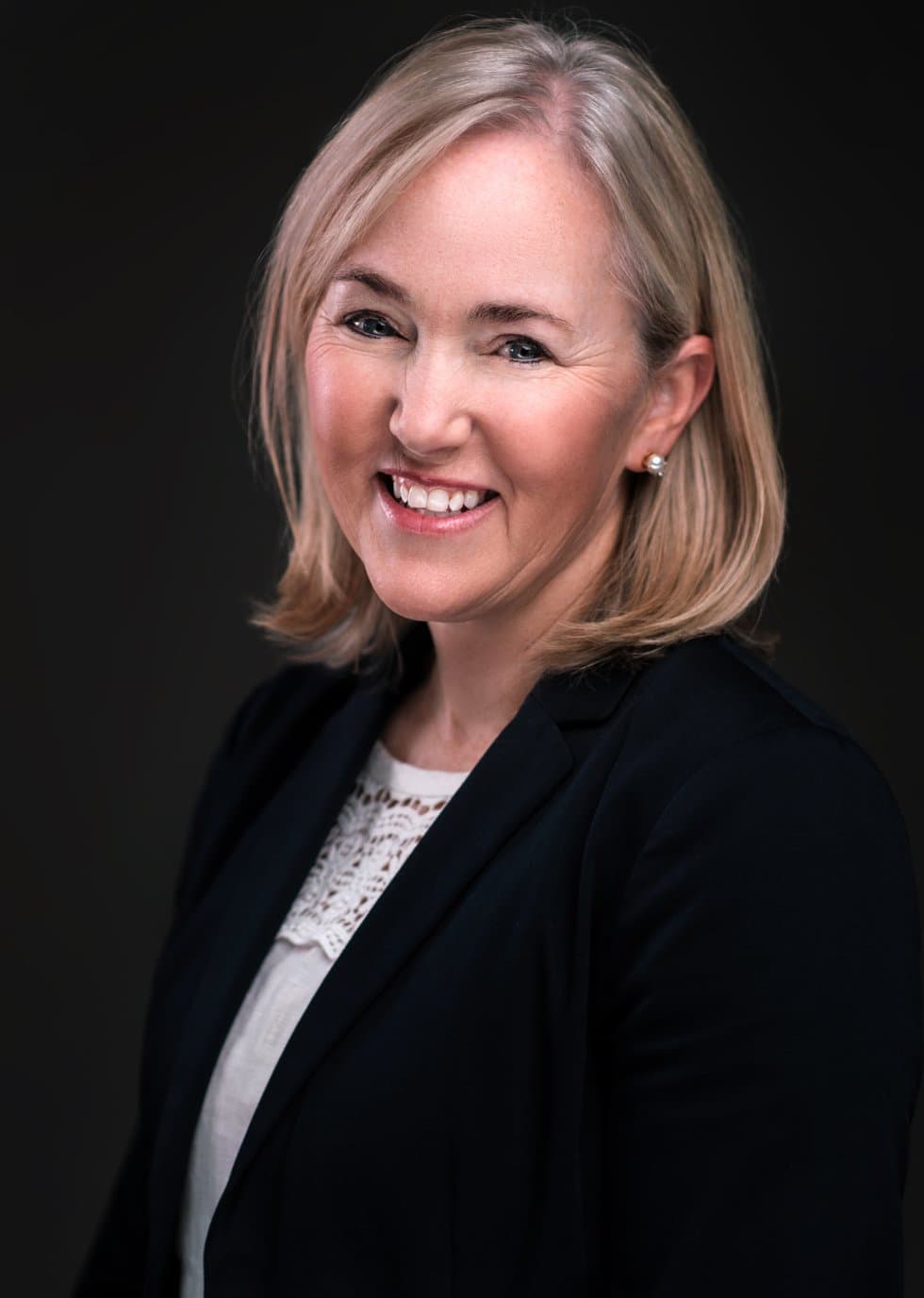 Woman with a blonde bob in a dark blazer, photographed at our headshot booth at a real estate trade show