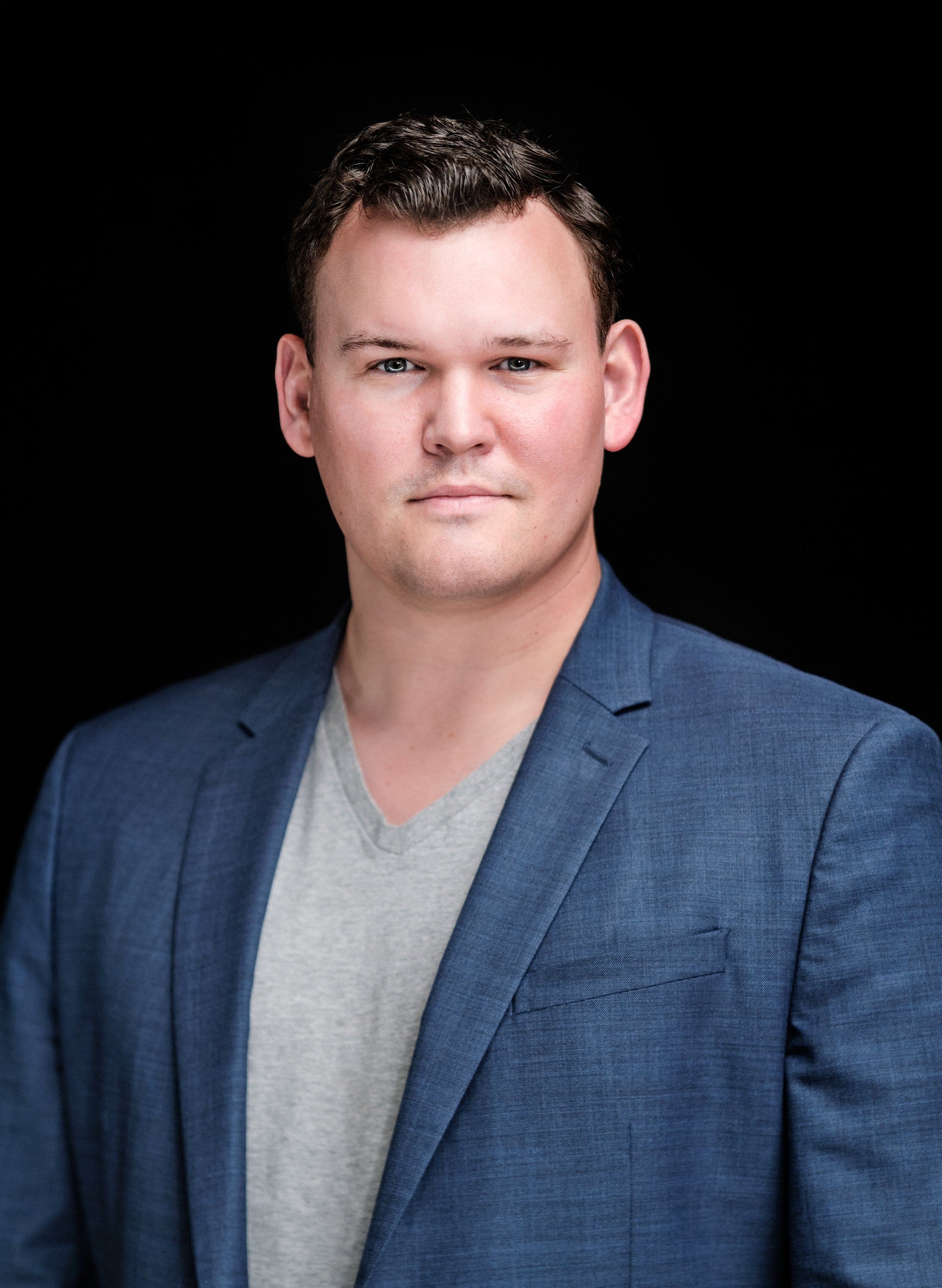 Man in a blue blazer over a grey T-shirt, photographed at our headshot booth at a surgery conference