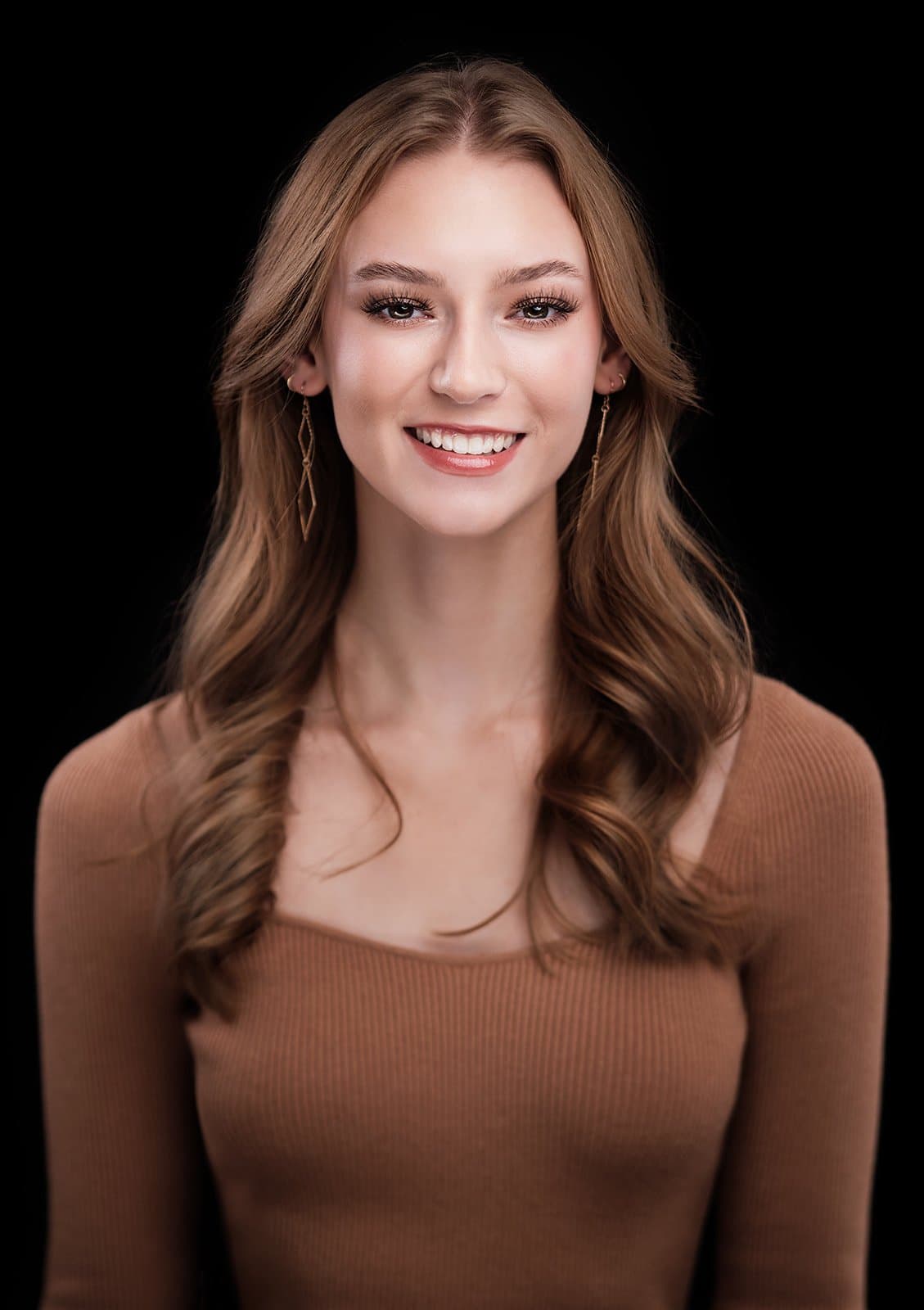 Woman with long auburn hair in a brown top, photographed at our headshot booth on a trade show floor