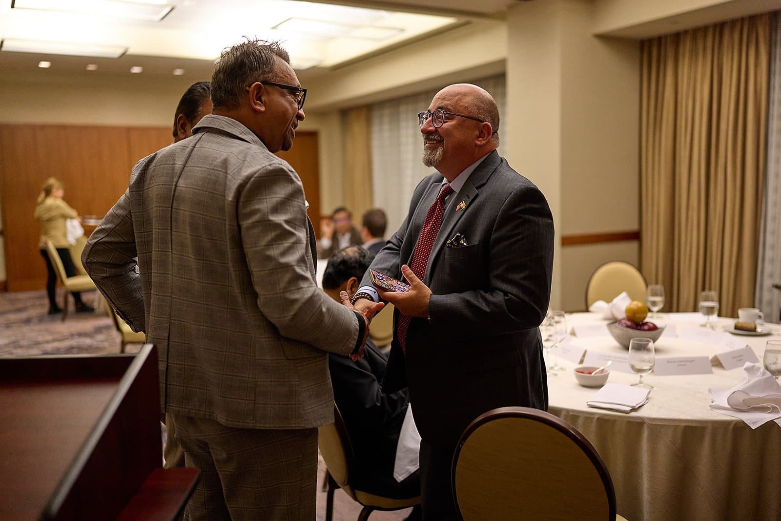 Two attendees talk beside set banquet tables at the US India Business Council conference in St. Louis