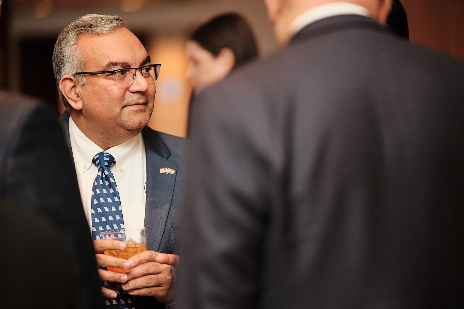 A guest holding a drink listens during a networking reception at the US India Business Council conference in St. Louis