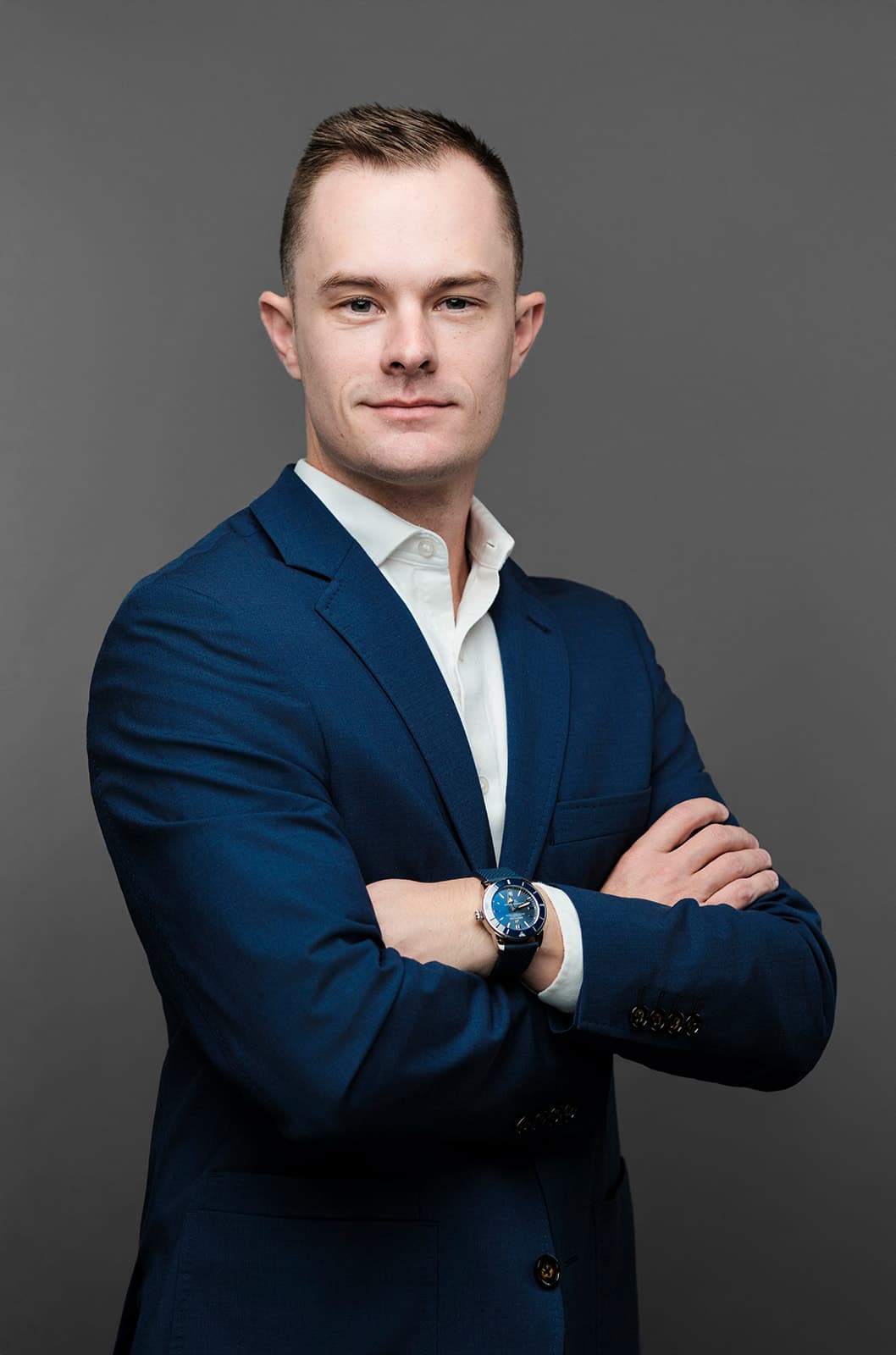 Young man with arms crossed in a navy blazer and white shirt, gray backdrop by Henry David Photography, the standard every Ladue headshot session is held to