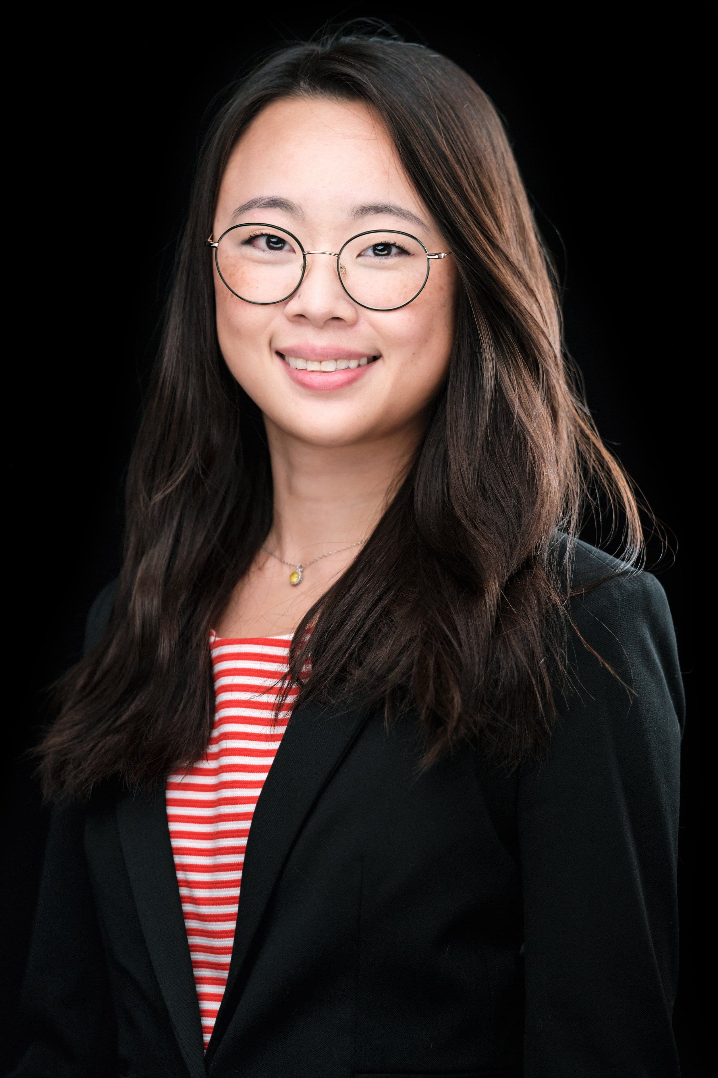 Smiling woman in round glasses, black blazer and striped top by Henry David Photography, the standard every Central West End headshot session is held to