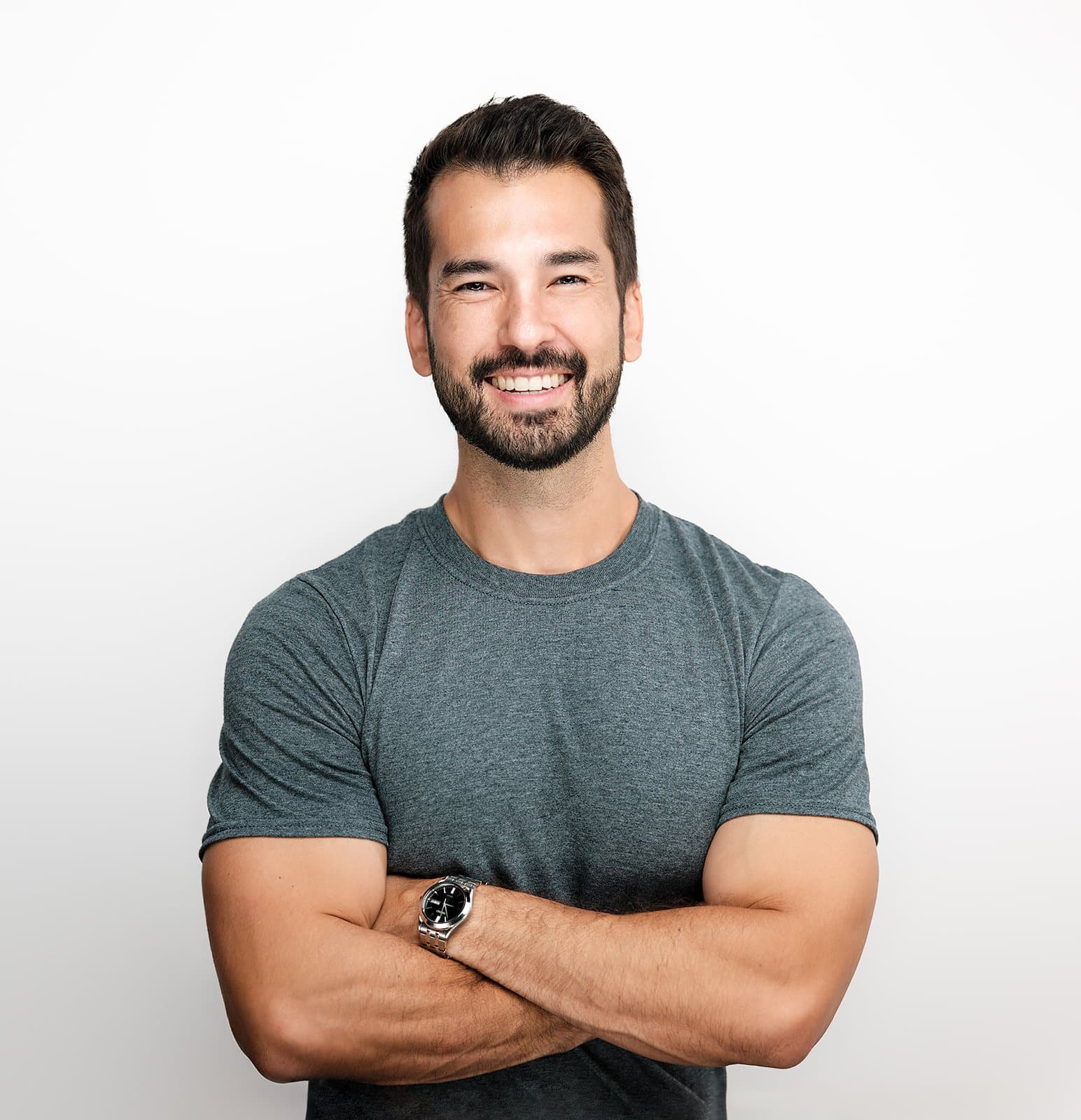 Henry David in a grey T-shirt with his arms crossed, smiling, against a white background