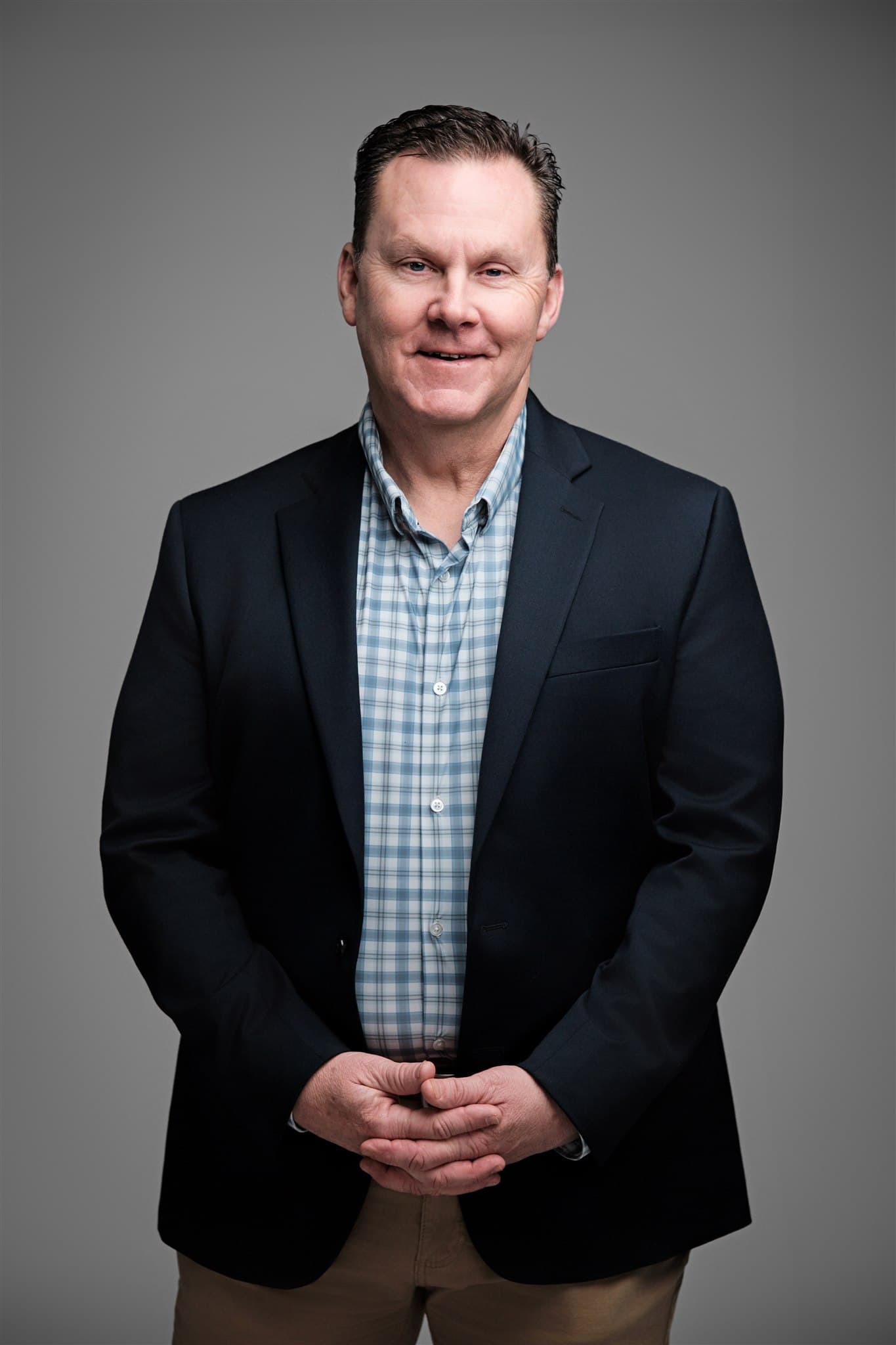 Smiling man in a dark blazer and checked shirt, gray backdrop by Henry David Photography, the standard every Chesterfield headshot session is held to