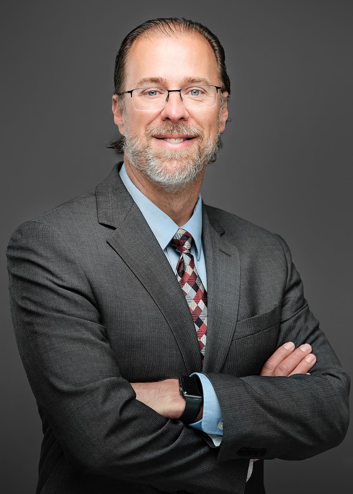 RubinBrown headshot, bearded man in glasses, gray suit and tie, arms crossed, by Henry David Photography
