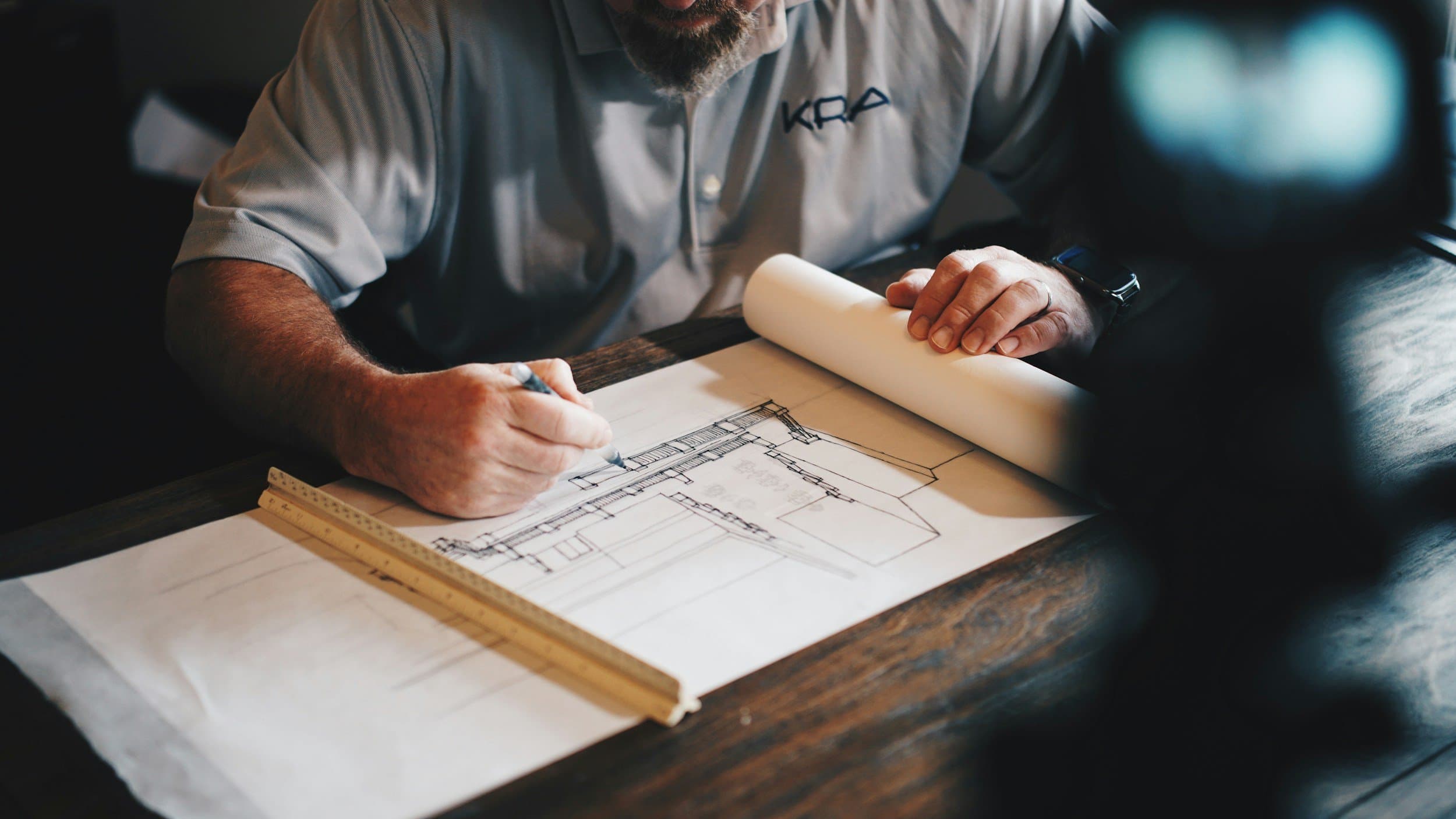 Architectural firm employee mid-task at a layout table, working environmental frame the kind we shoot for law firm marketing collateral