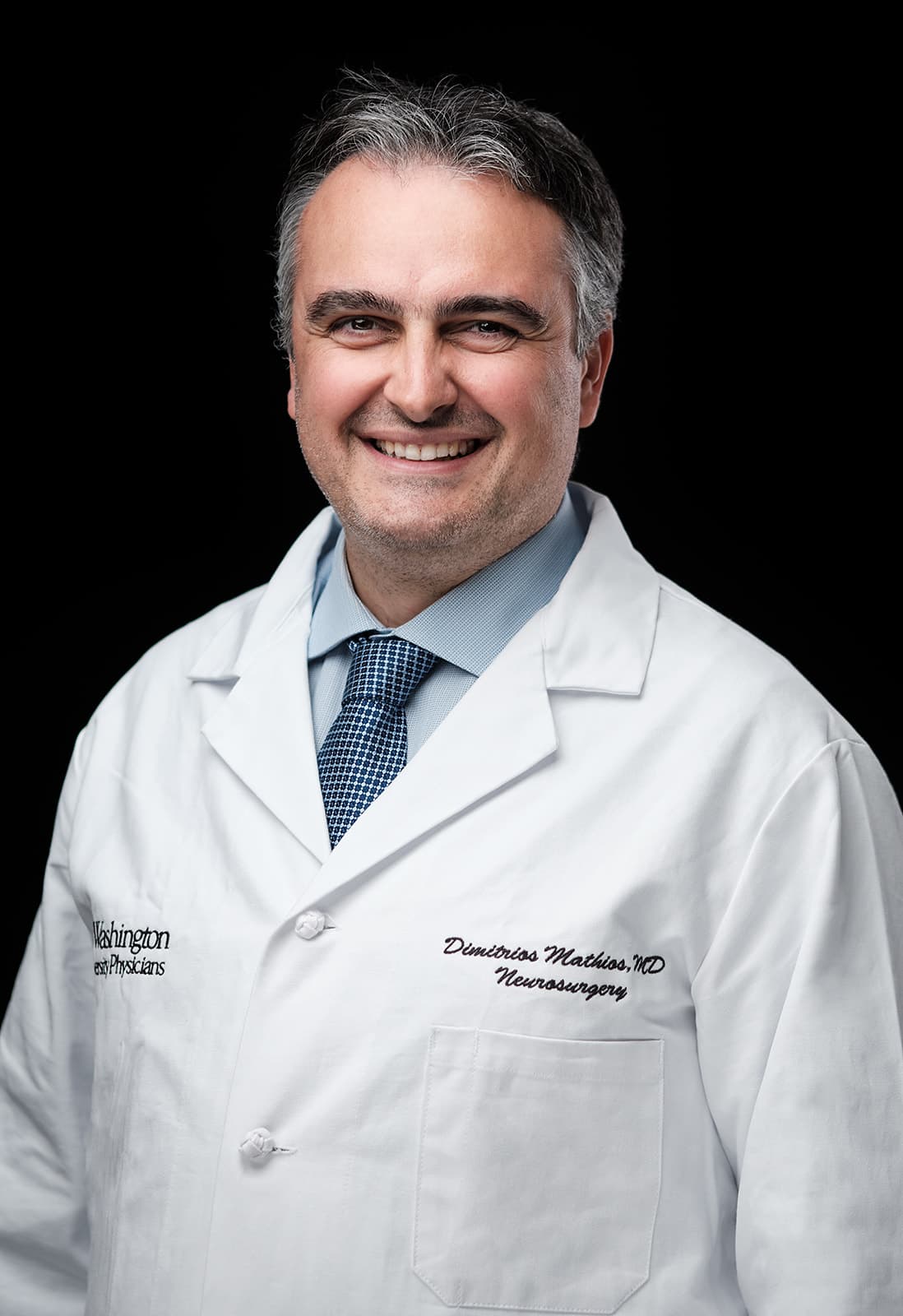 Dr. Dimitrios Mathios, WashU Neurosurgery, white coat headshot on black backdrop by Henry David Photography