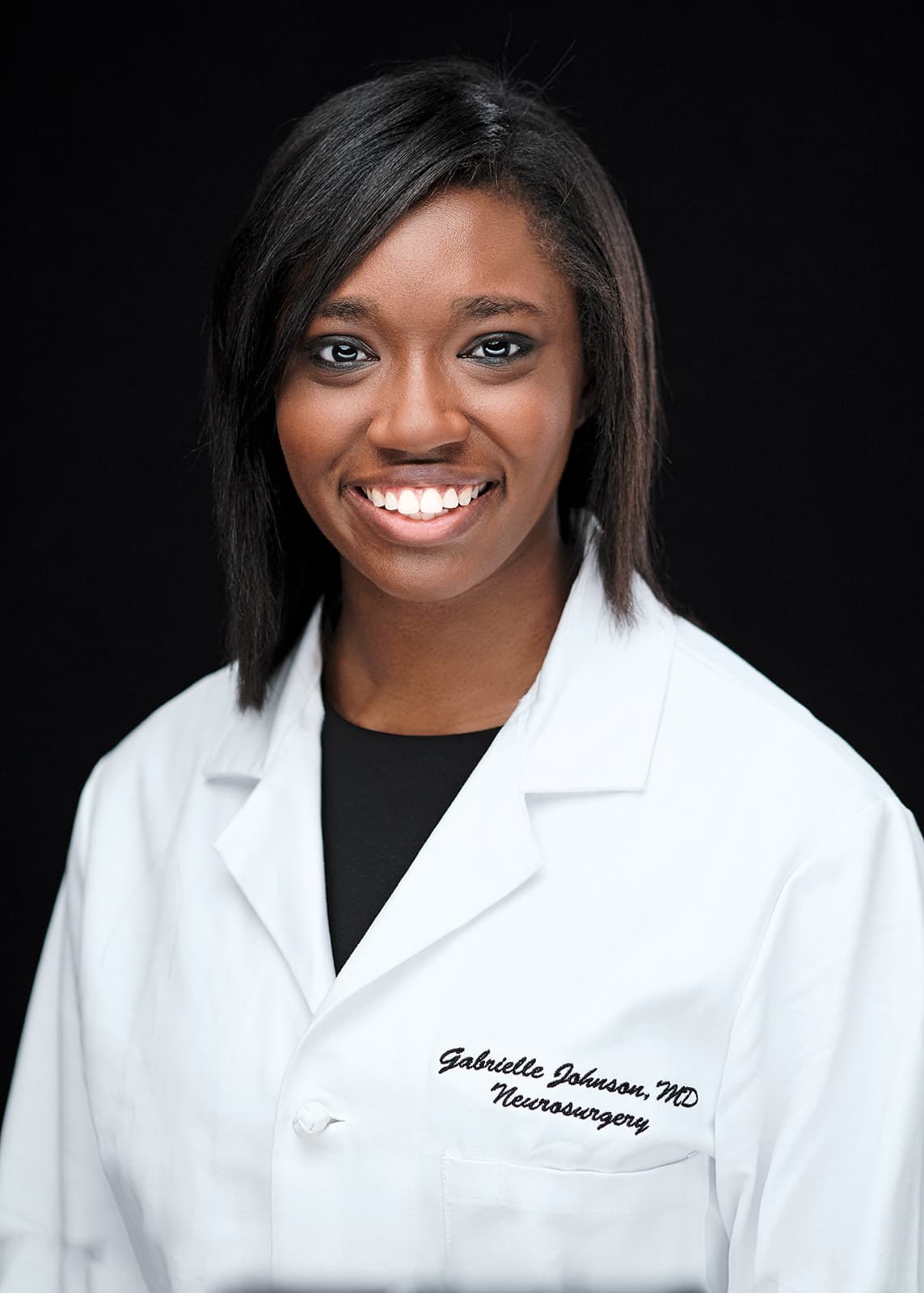 Dr. Gabbie Johnson, WashU Neurosurgery, white coat headshot on black backdrop by Henry David Photography