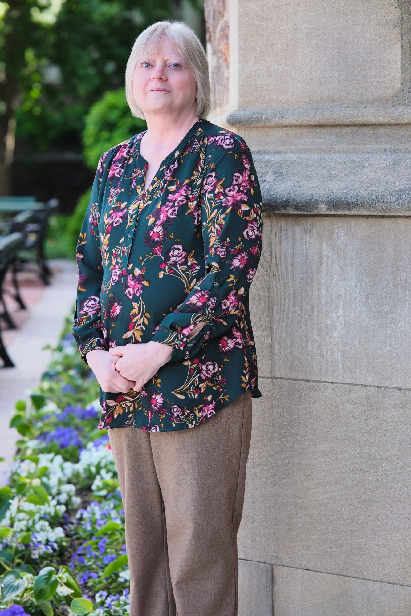 MHS Legacy team member in a green floral blouse photographed in the spring garden courtyard at Washington University Brookings Hall by Henry David Photography