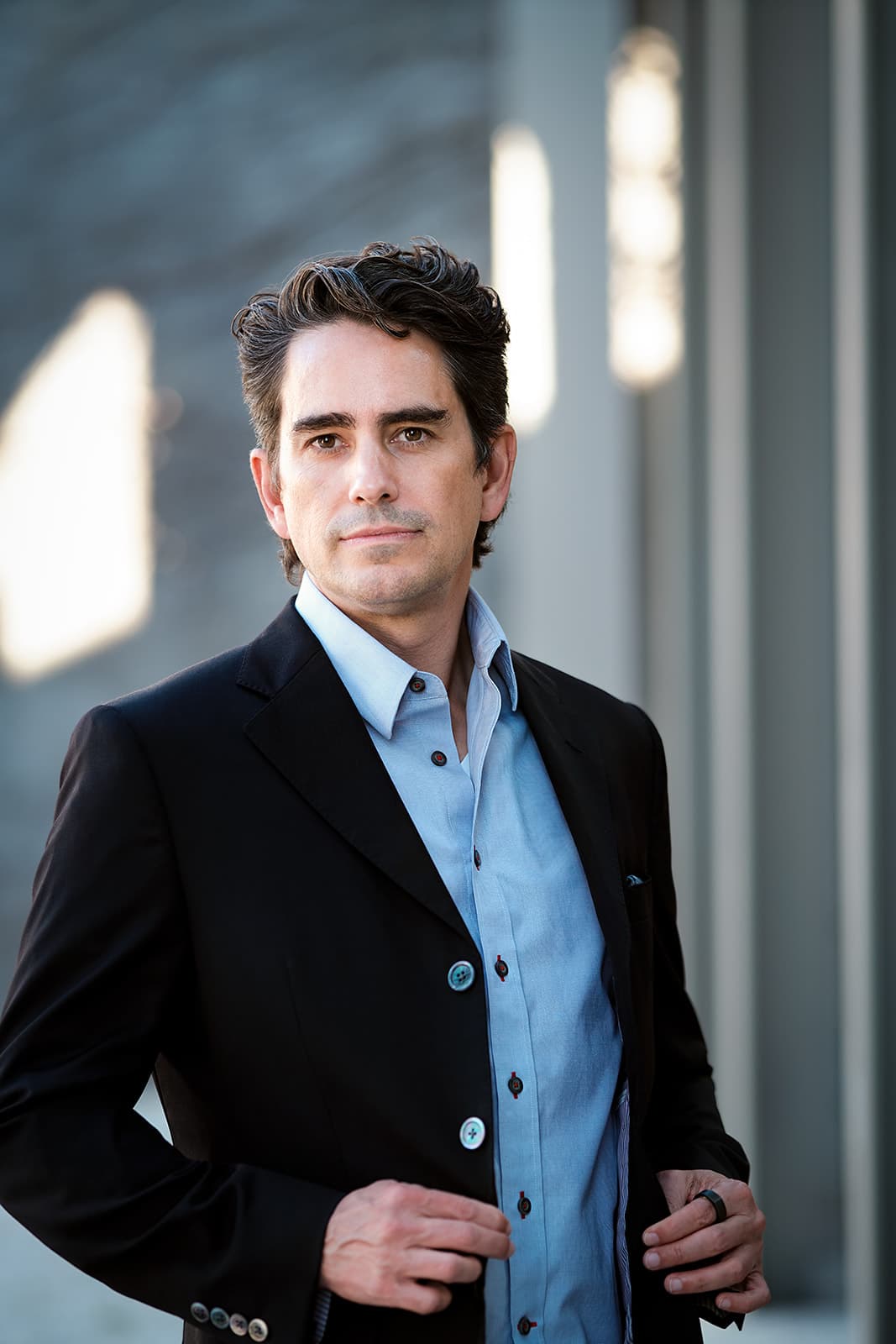 Walker Deibel author portrait in black blazer against architectural columns, used for book marketing and press